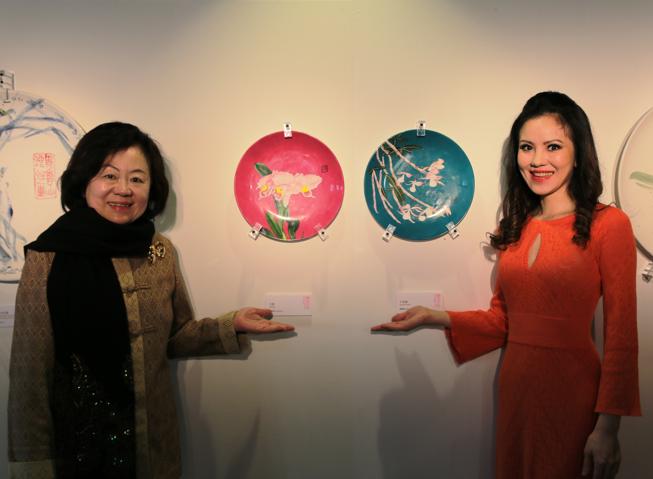 公視董事長陳郁秀（左）、知名鋼琴家盧佳慧（右）與藝術家陳慧坤的作品《洋蘭》（紅色）、《牛蒡蘭》（青色）。
