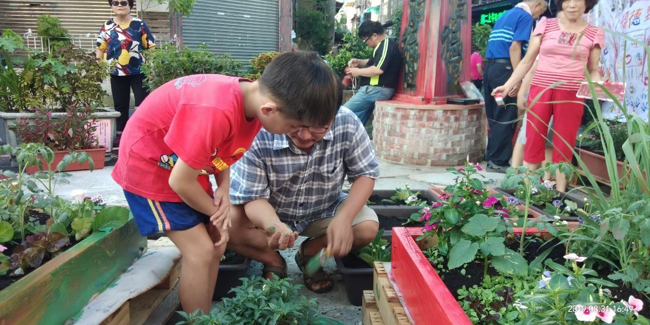 輔導團老師帶著小朋友一起彩繪木棧板改造的花圃