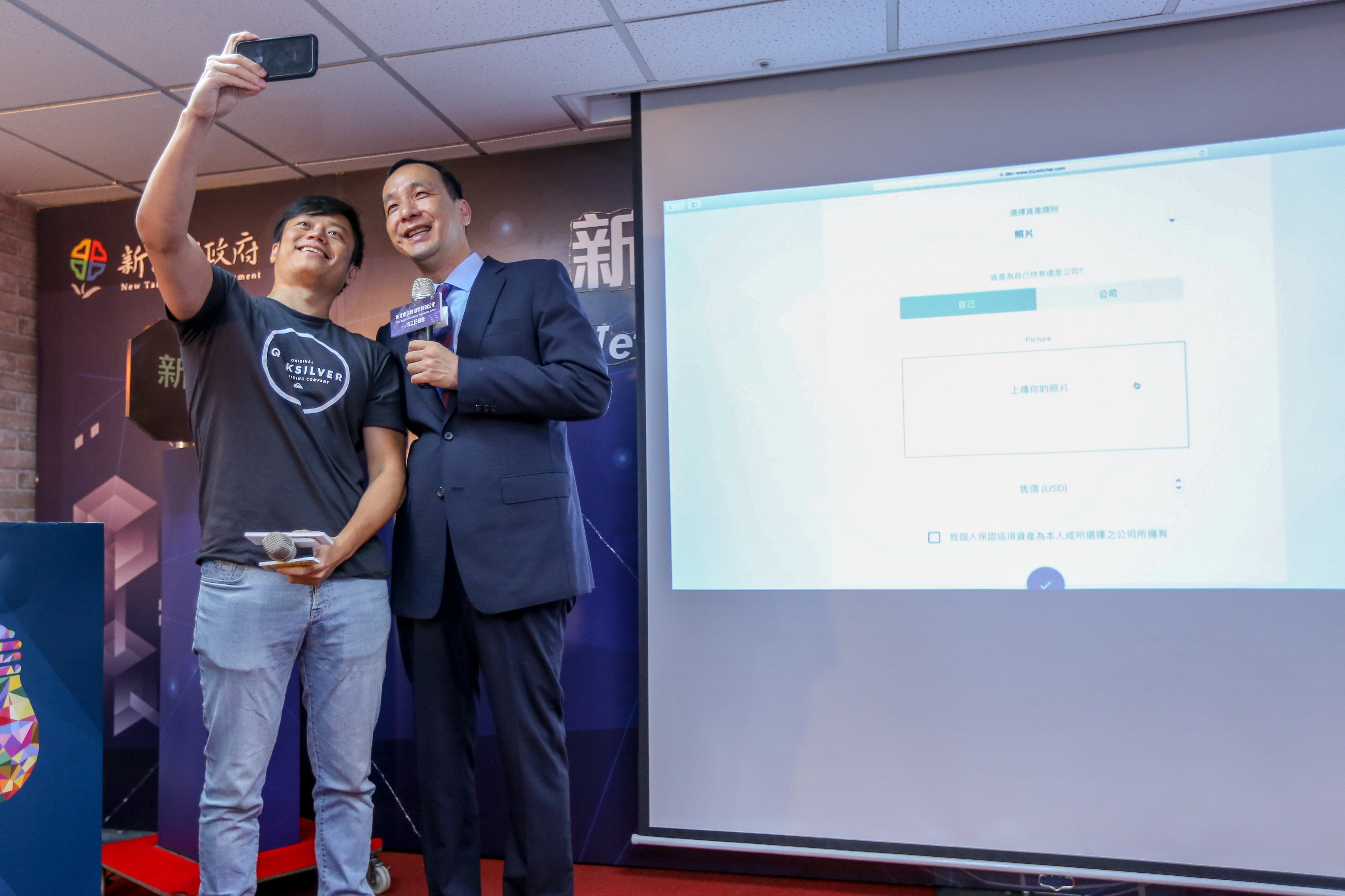新北市長朱立倫(右)現場透過BizWitcher收併購平台拍賣自拍照，體驗區塊鏈技術應用