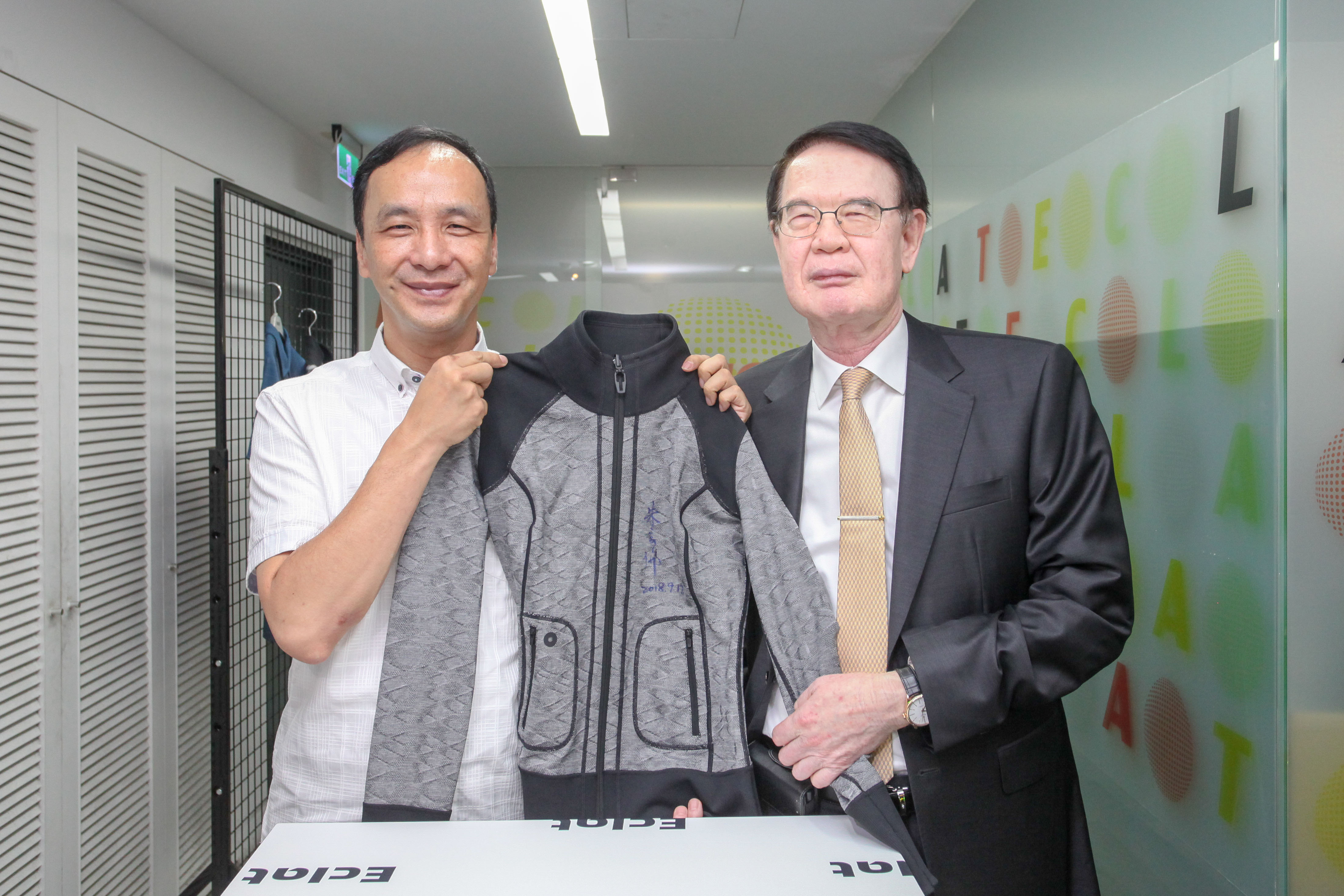 新北市長朱立倫(左)與儒鴻企業董事長洪鎮海(右)一同與簽名外套合影