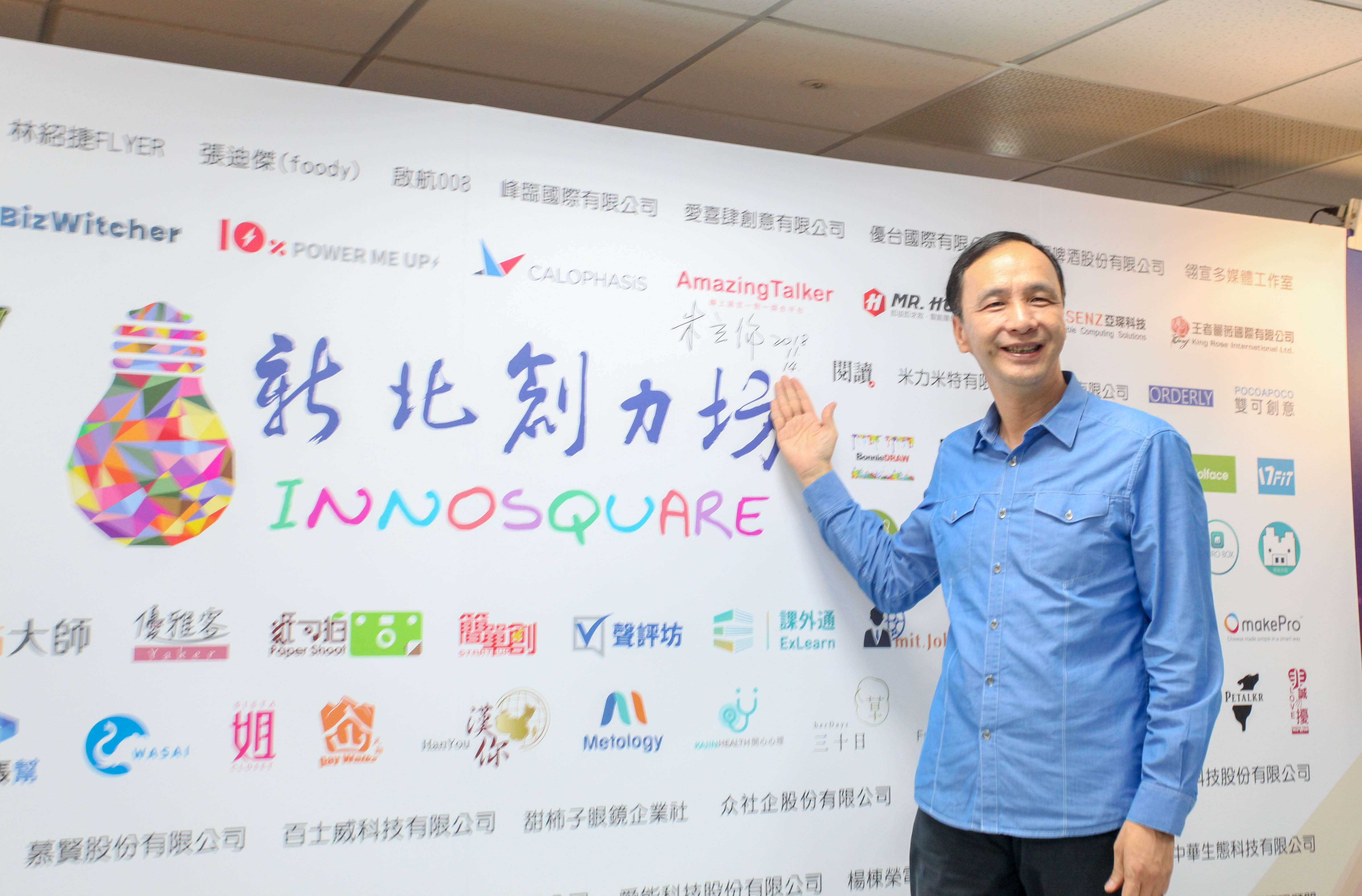 新北市長朱立倫於新北創力坊歷屆團隊logo板上簽名留念