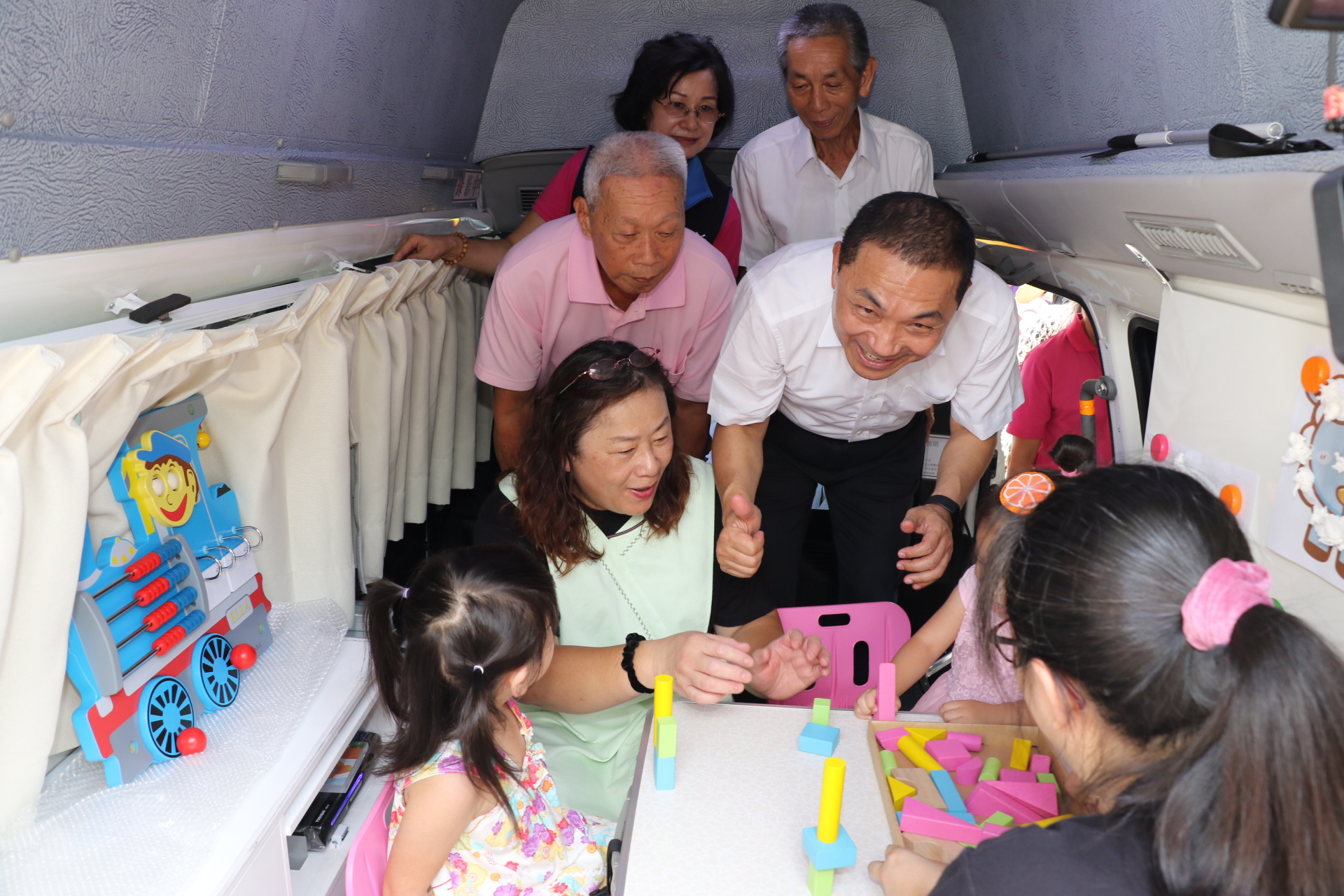 侯友宜和在行動車前玩篩檢教材的孩子親切互動