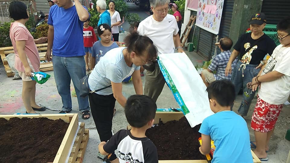 鄰里夥伴一起將填入泥土填入花圃中
