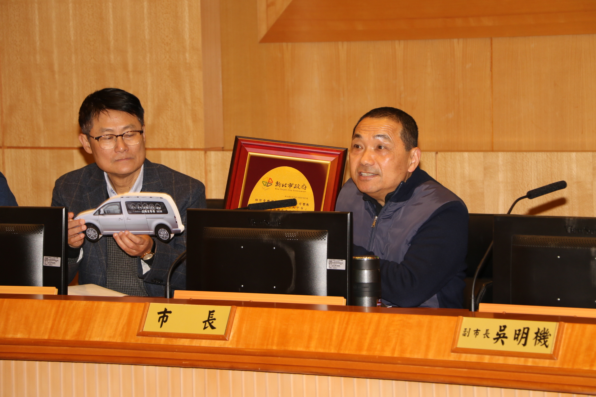 侯友宜在市政會議中宣布  五月天透過經紀公司「相信音樂」捐贈10輛福斯七人座車給新北市  做為偏區長輩交通之用  侯友宜手中的感謝牌將透過經紀公司轉贈
