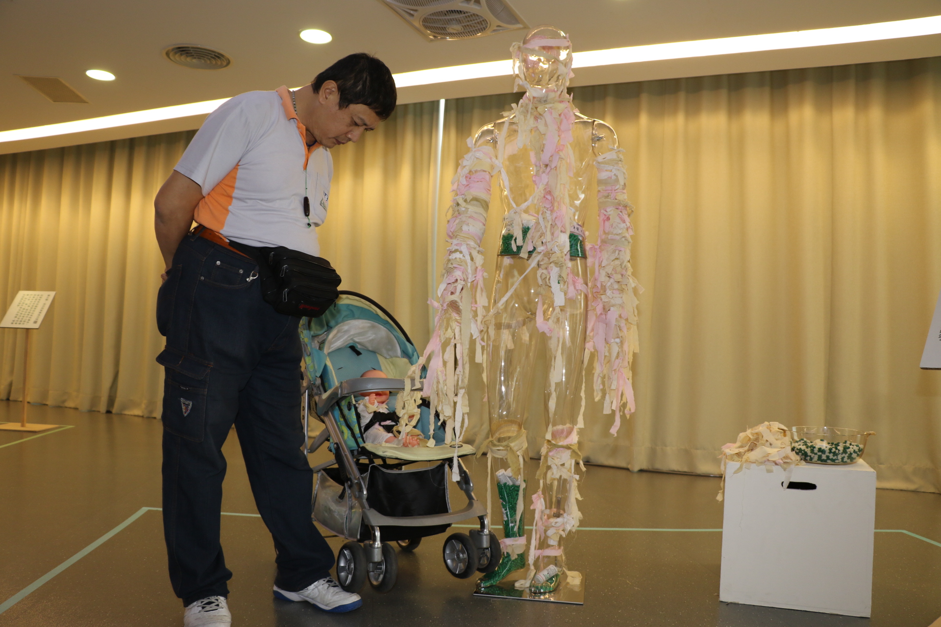 炎清重製3年前在電梯內遭娃娃車輾腳的畫面  這事困擾了他3年  右邊是觀展者有投藥  更多的是綁上理解的粉紅絲帶