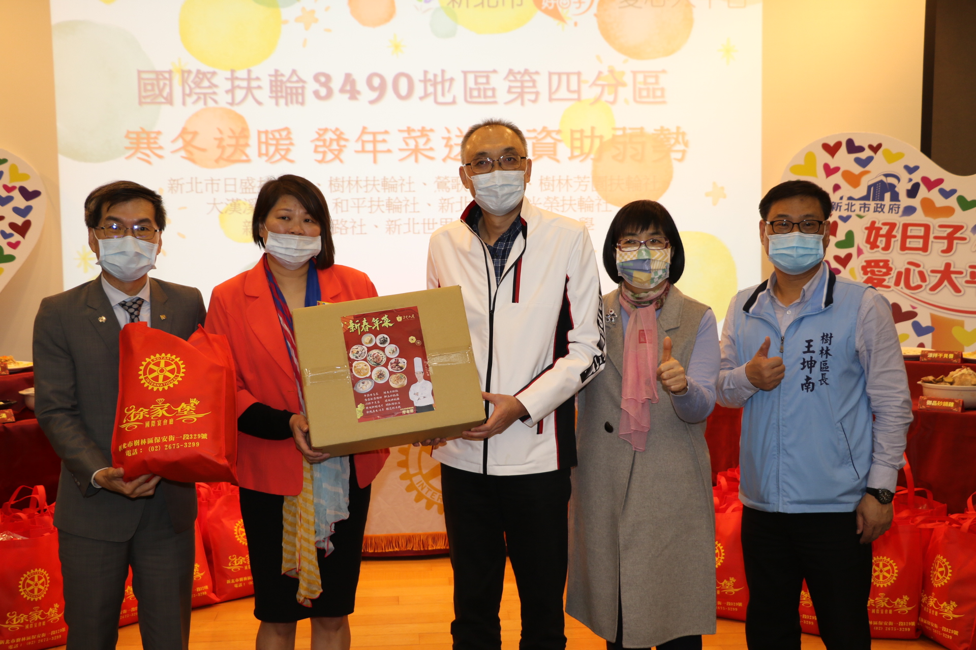 左起國際扶輪3490地區總監陳向緯、主辦社新北市日盛扶輪社社長陳芊諭代表捐贈十全十美開運年菜  由謝政達、張錦麗局長、王坤南區長等人代表受贈