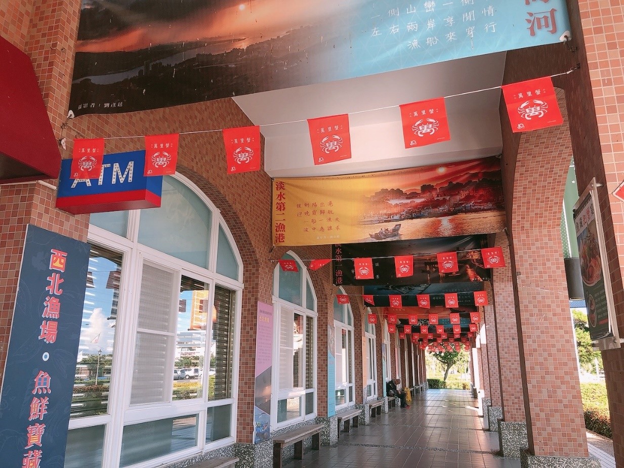 圖二：淡水漁市外長廊以紅磚為為牆面，再加上色的萬字旗，別有老街的風味