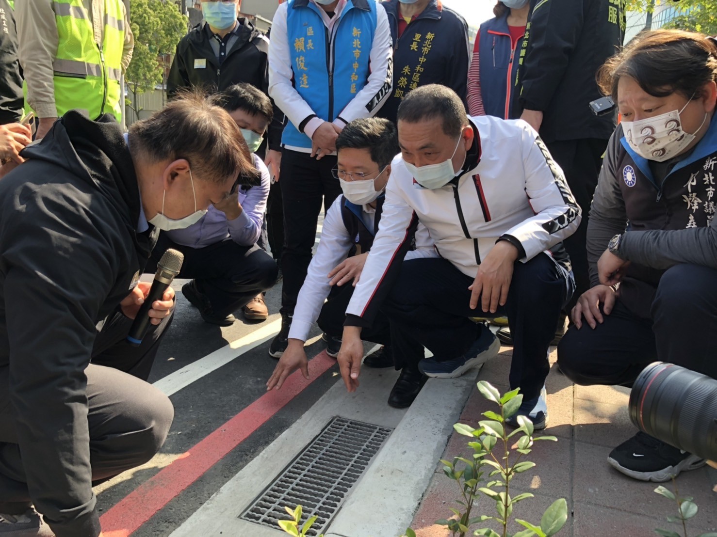 養工處長馮兆麟（左）向侯友宜市長等一行人說明，人行道施工時，特別施作一種直混合的落式及側進式排水溝，以加快排水效率，減少積淹水發生。