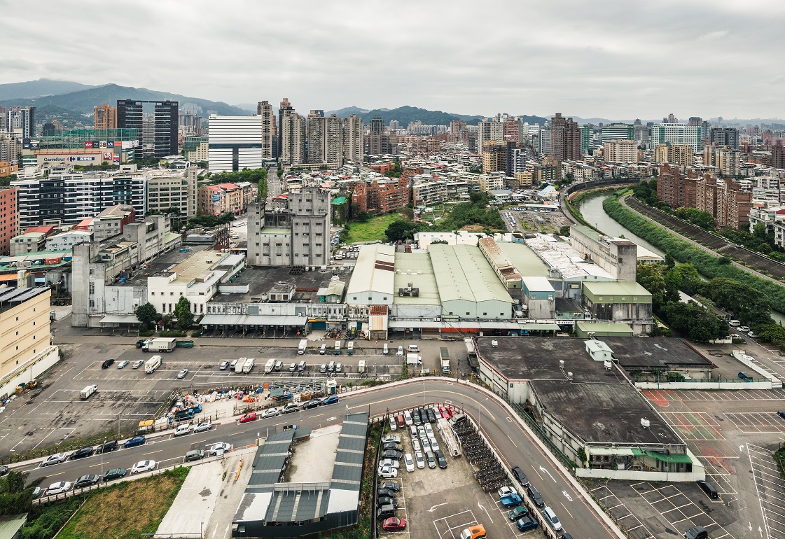 新店榮工單元2位於新店區東北隅，北側以景美溪為界與台北市文山區相鄰，計畫區內現況主要為正大尼龍工業之倉儲及辦公使用，而西側多為老舊低矮住宅，東側主要為停車場使用，南側為裕隆、宏達電等企業總部及大型賣場如家樂福等。