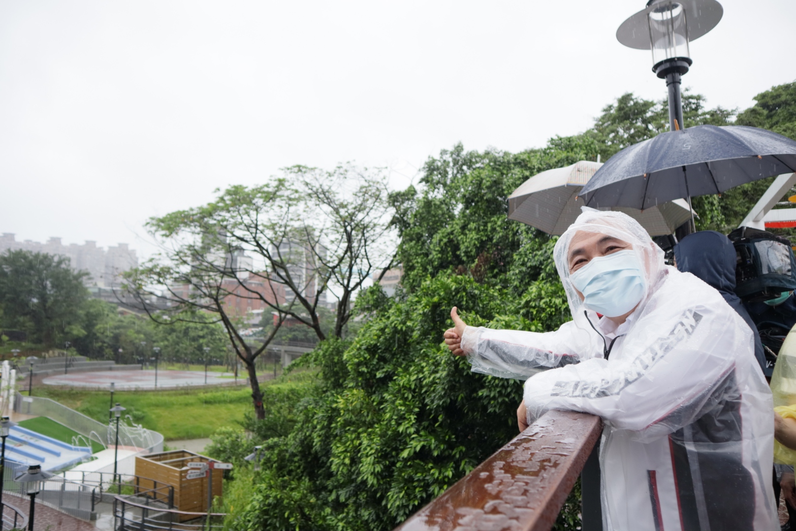 新北市長侯友宜在陰雨綿綿之下穿戴雨衣主持汐止水返腳公園啟用典禮