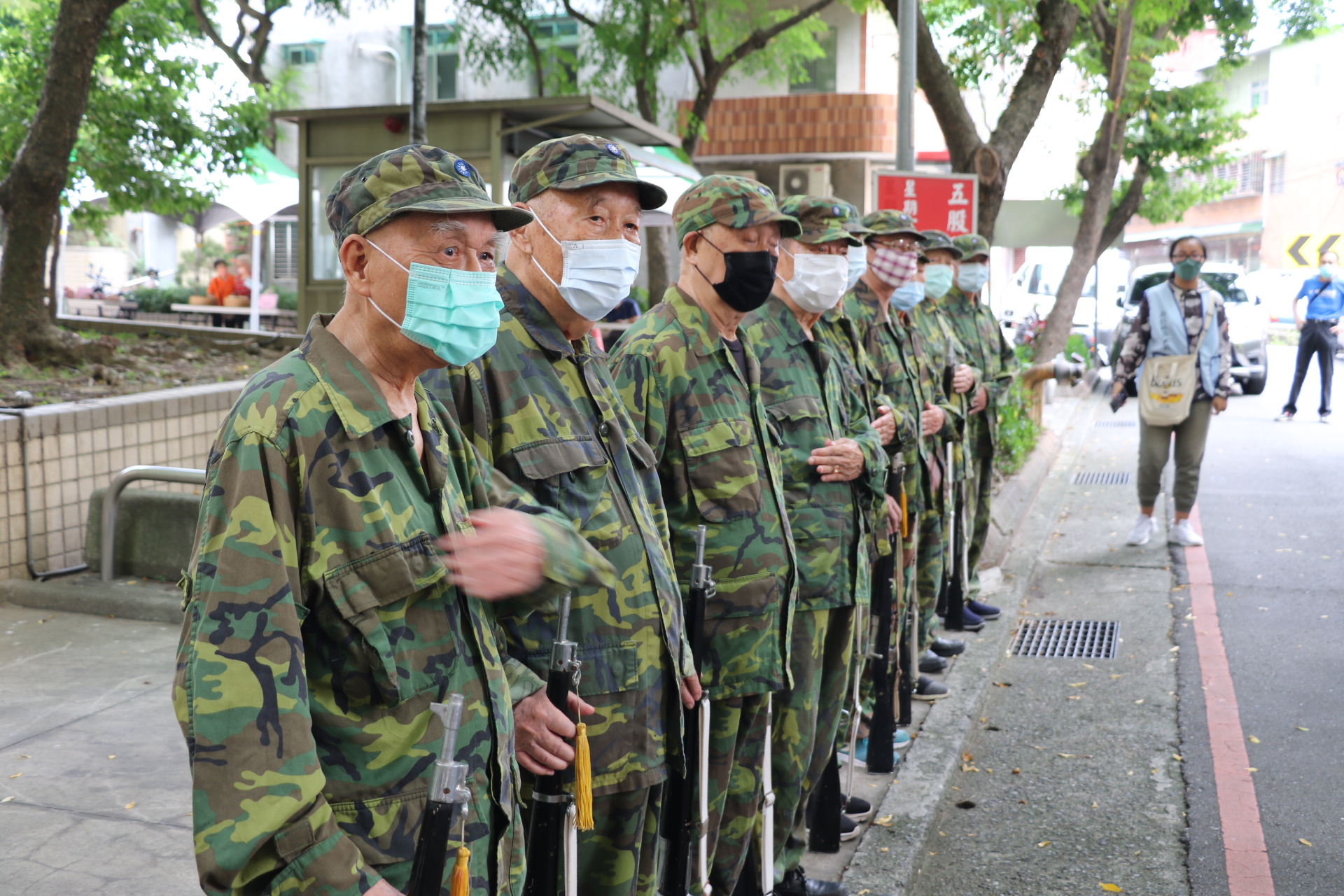 衛福部選拔金卓越社區的委員訪視五股貿商  超過90歲的爺爺穿上迷彩裝歡迎  為首的是劉國康  今年已經94歲   喊起立正--敬禮--  聲音宏亮  令委員印象深刻