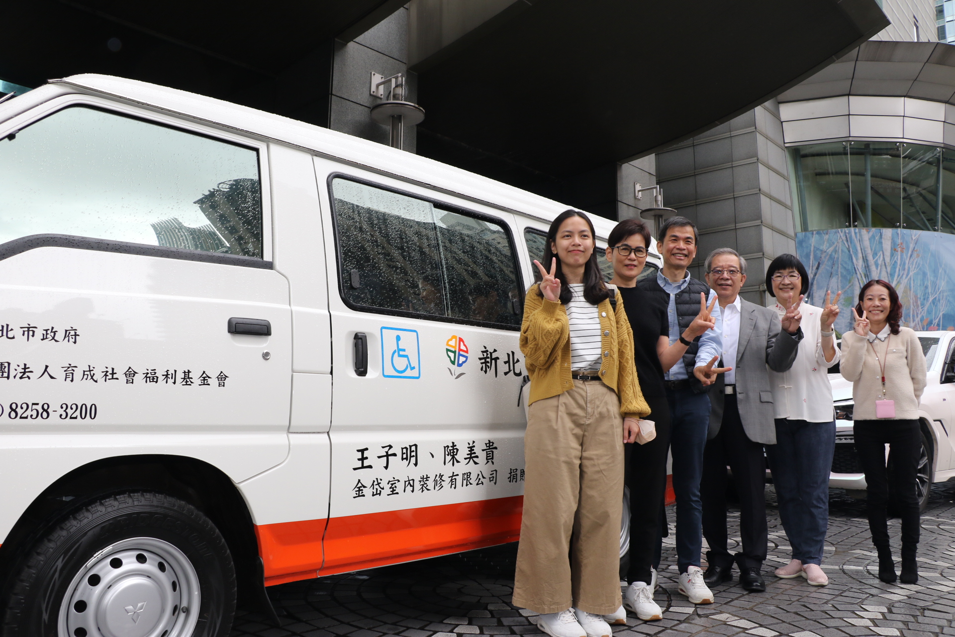 室內設計師陳美貴（左2）和先生王子明（左3）開心帶著女兒一起捐贈復康巴士作為退休禮  由新北市府秘書長林祐賢（右3）、社會局長張錦麗（右2）、交通局副局長林麗珠（右1）等人代收