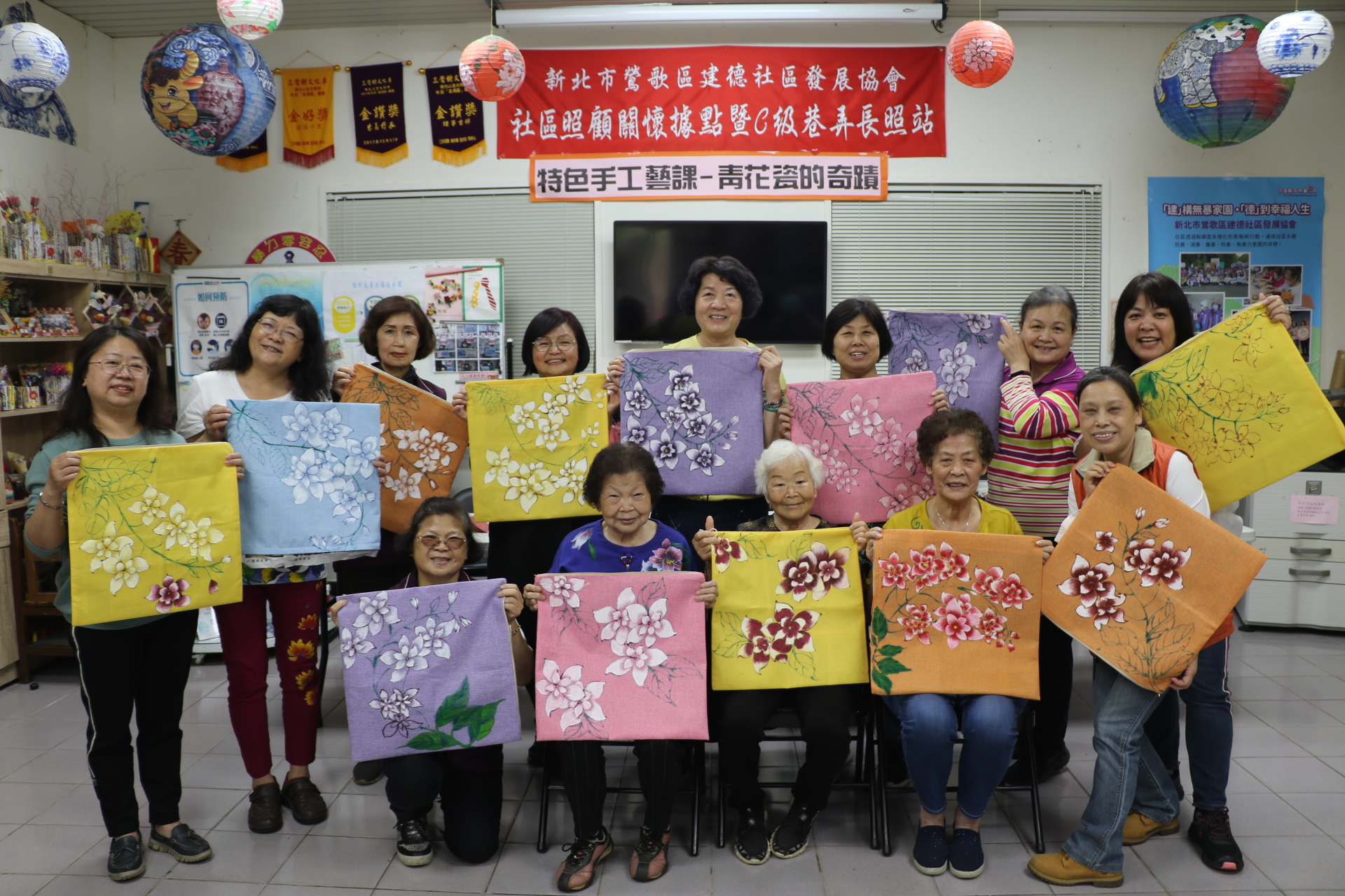鶯歌建德社區青花瓷班長輩秀出自繪的抱枕套作品許願藤花  後排右1為協會總幹事林郁君