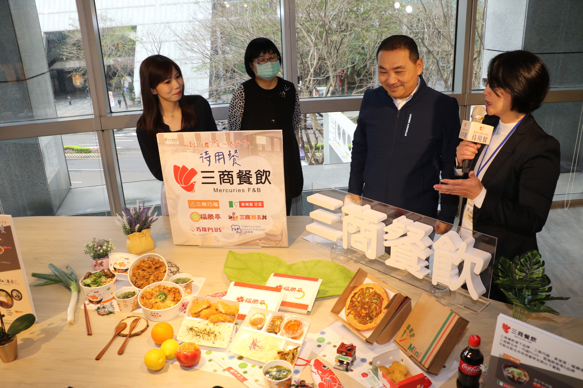 三商餐飲行銷經理洪以倩（右）向侯友宜說明該公司的待用餐包含比薩、炸雞等