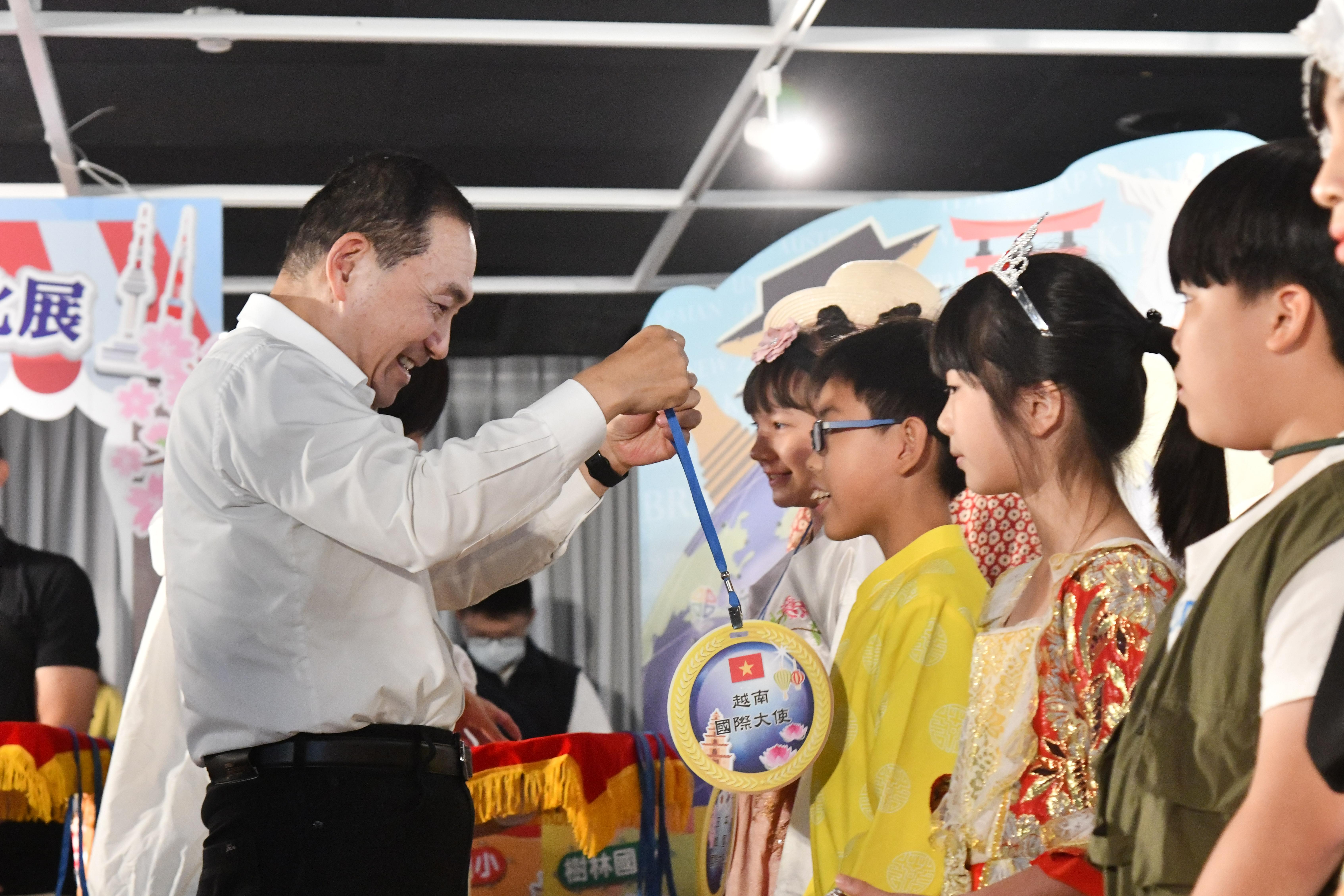 侯友宜為小朋友們掛上國際大使牌以示授證。