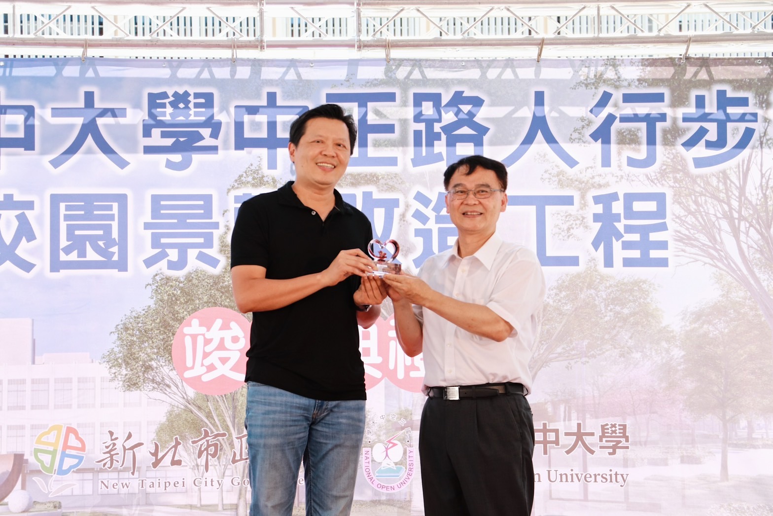 新北市副市長朱惕之（左）代表侯市長當場致贈空中大學一座感謝獎盃，感謝陳松柏校長（右）及空大打開校園面向社區，與居民分享優美的校園環境，讓社區與學校零距離。