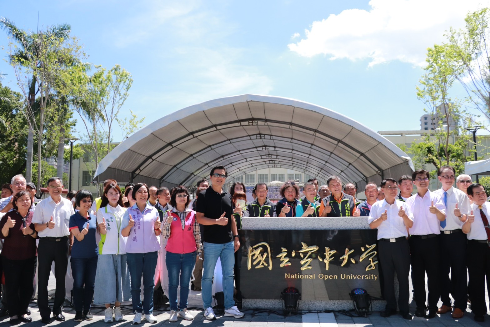 朱惕之副市長（右5）空中大學校長陳松柏（右4）、地方民意及與會貴賓在改善完工後的校門口一同合影留念，期待空大能和蘆洲地方有更多的連結，進而結合地商圈、文教、古蹟、民俗技藝，吸引更多人來蘆洲漫遊。
