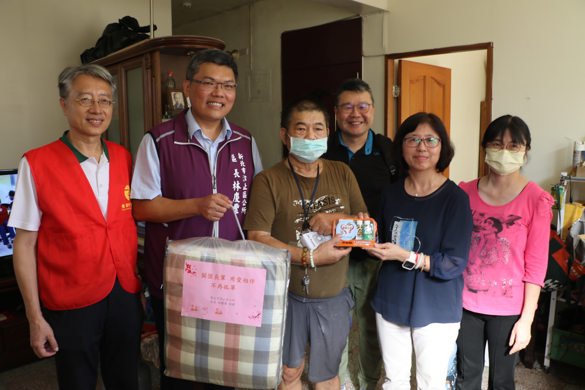 靈鷲山慈善基金會副執行長陳世人（左1）及虹冠電子經理陳寶福（右3）和許秀能副局長（右2）、林慶豐區長（左2）聯袂關懷廖伯伯