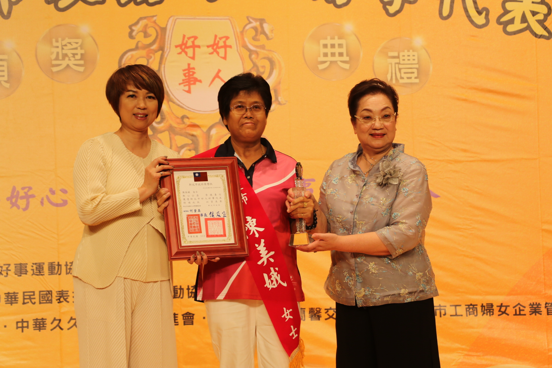 多元志工陳美娥當選新北市好人好事代表 由新北市府副秘書長龔雅雯（左）和新北市表揚好人好事運動協會理事長何碧英（右）頒贈榮譽狀