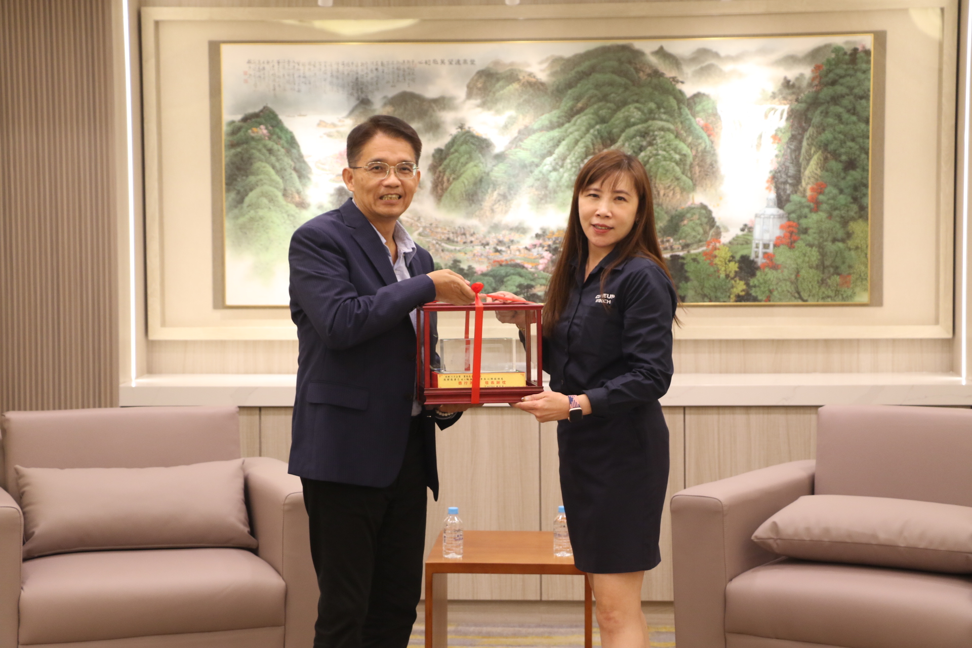  新北市政府秘書長邱敬斌代表侯友宜市長回贈復康巴士模型車給寶春基金會財務長黃家玲（右）
