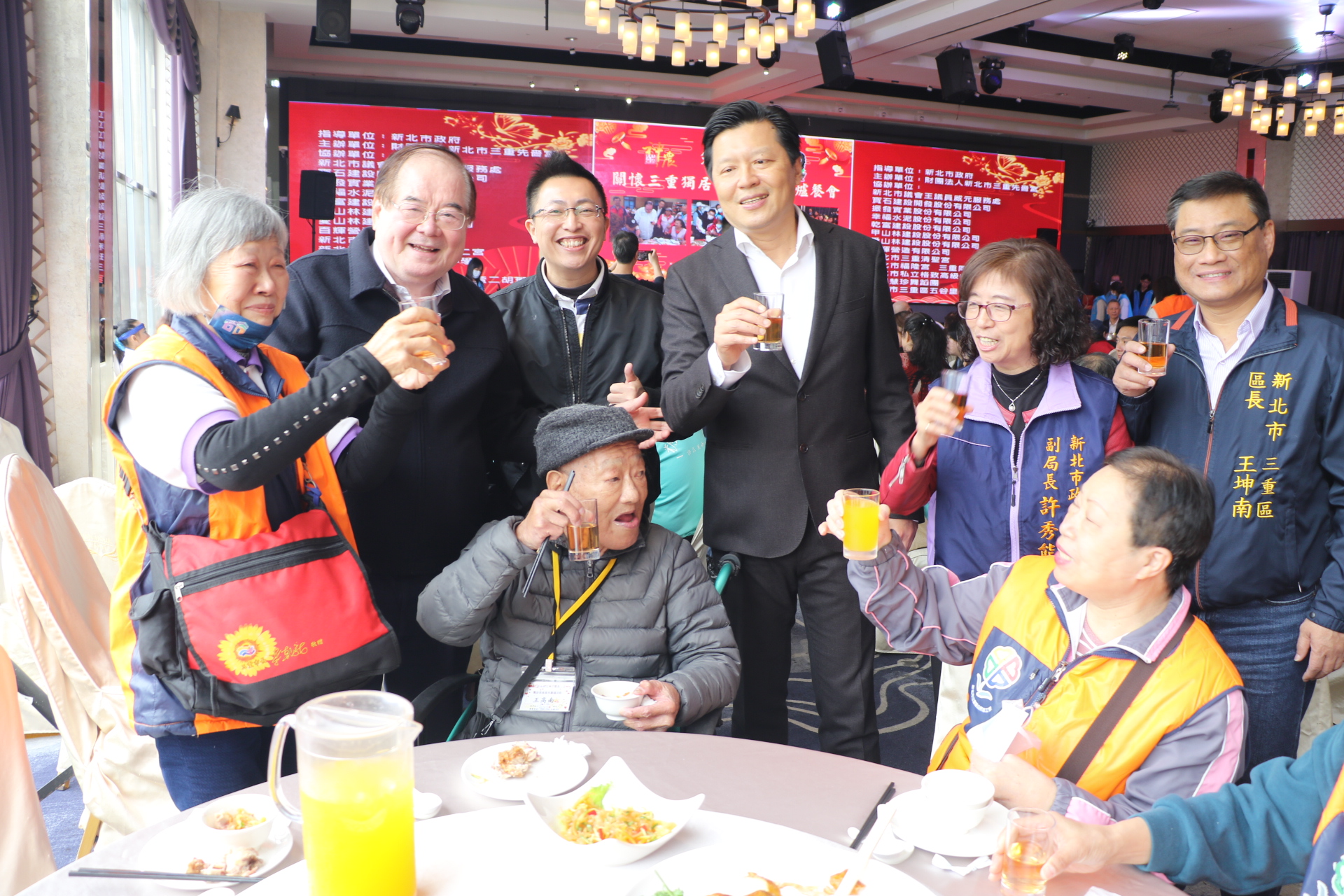 今年72歲的林招治（左1）揹著當年志工隊成立時市長送的紅色小書包服務 朱惕之（左4）和李乾龍（左2）、王威元議員（左3）等人一起向長輩致意