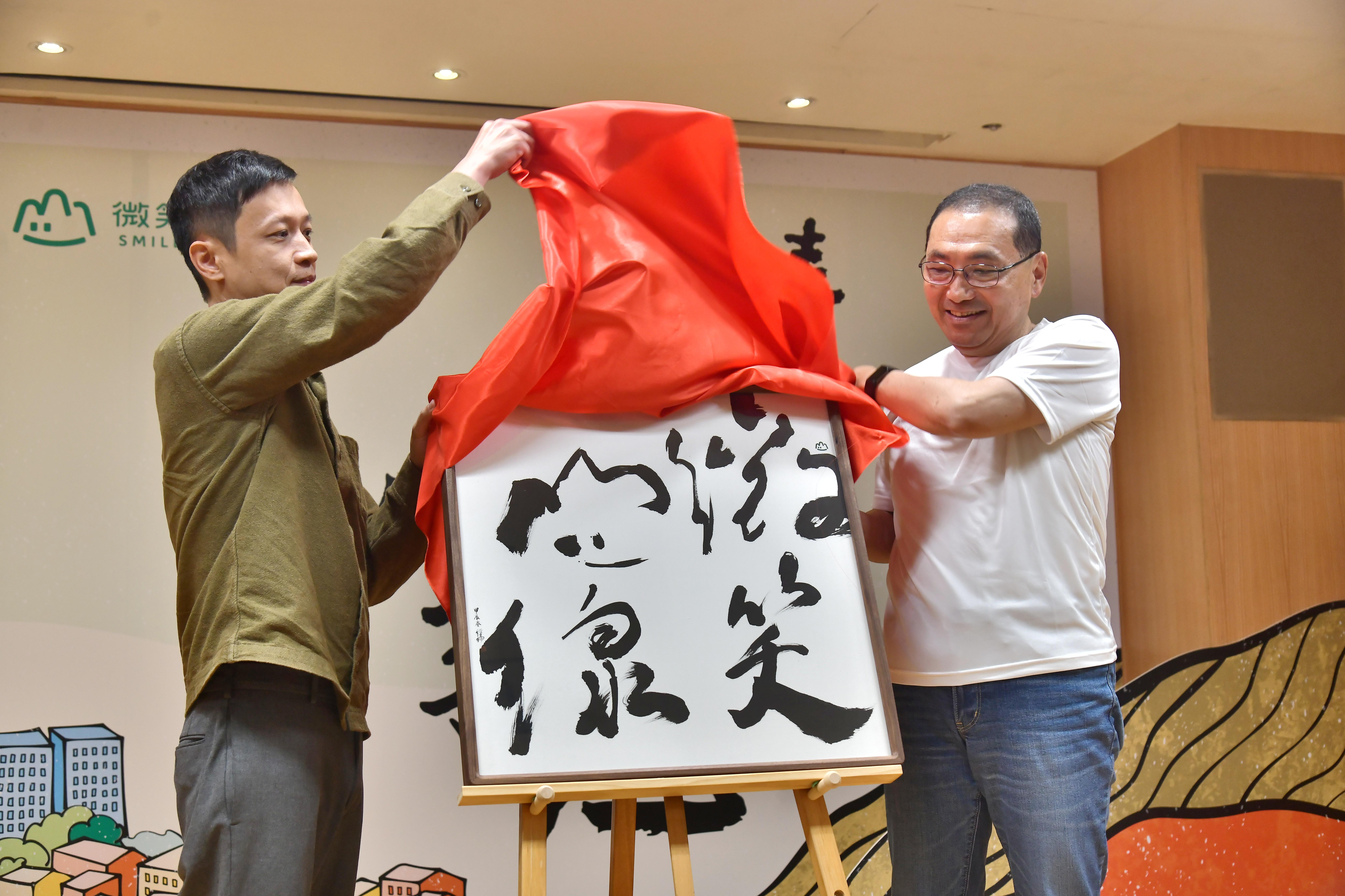新北市政府邀請台灣知名青年書法藝術家徐經綸(左)為「微笑山線」服務據點設計識別牌