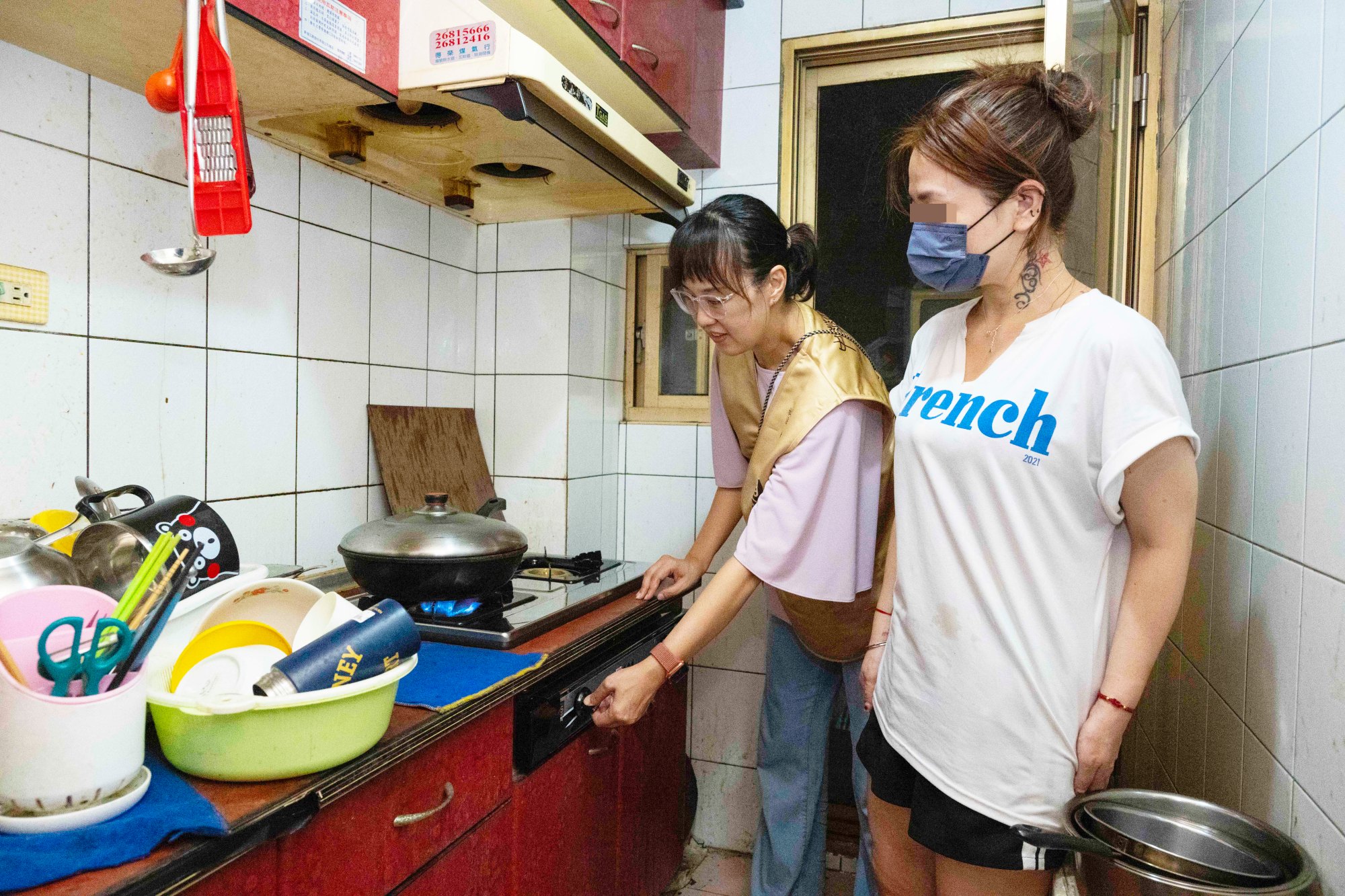  道家人文協會志工組長劉美良（左）試開新瓦斯爐具 右為板橋陳姓單親媽媽