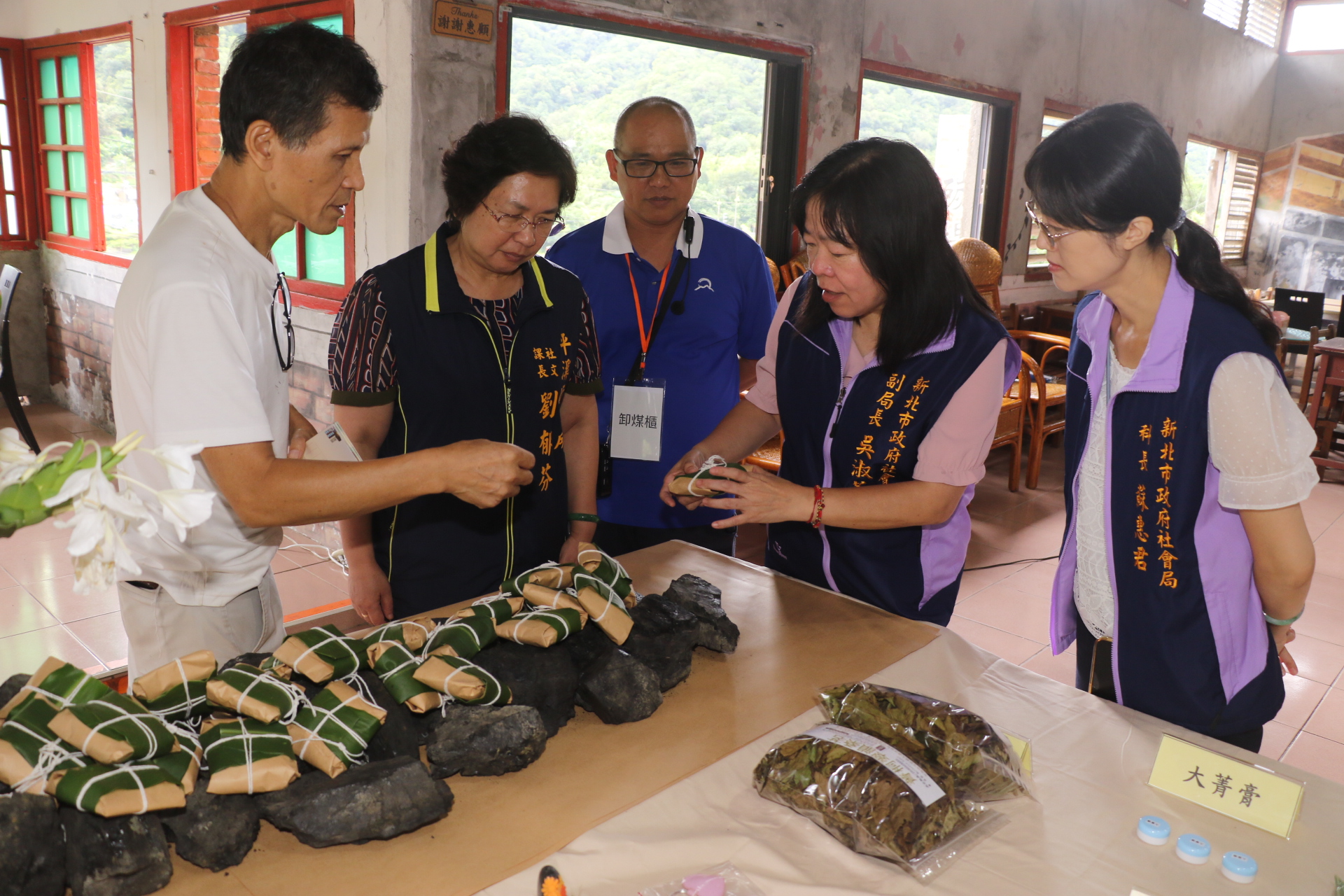 平溪電子天燈館長詹林欽（左） 為吳淑芳副局長說明礦光入坑前便當外 會另帶用野薑花包著的飯糰