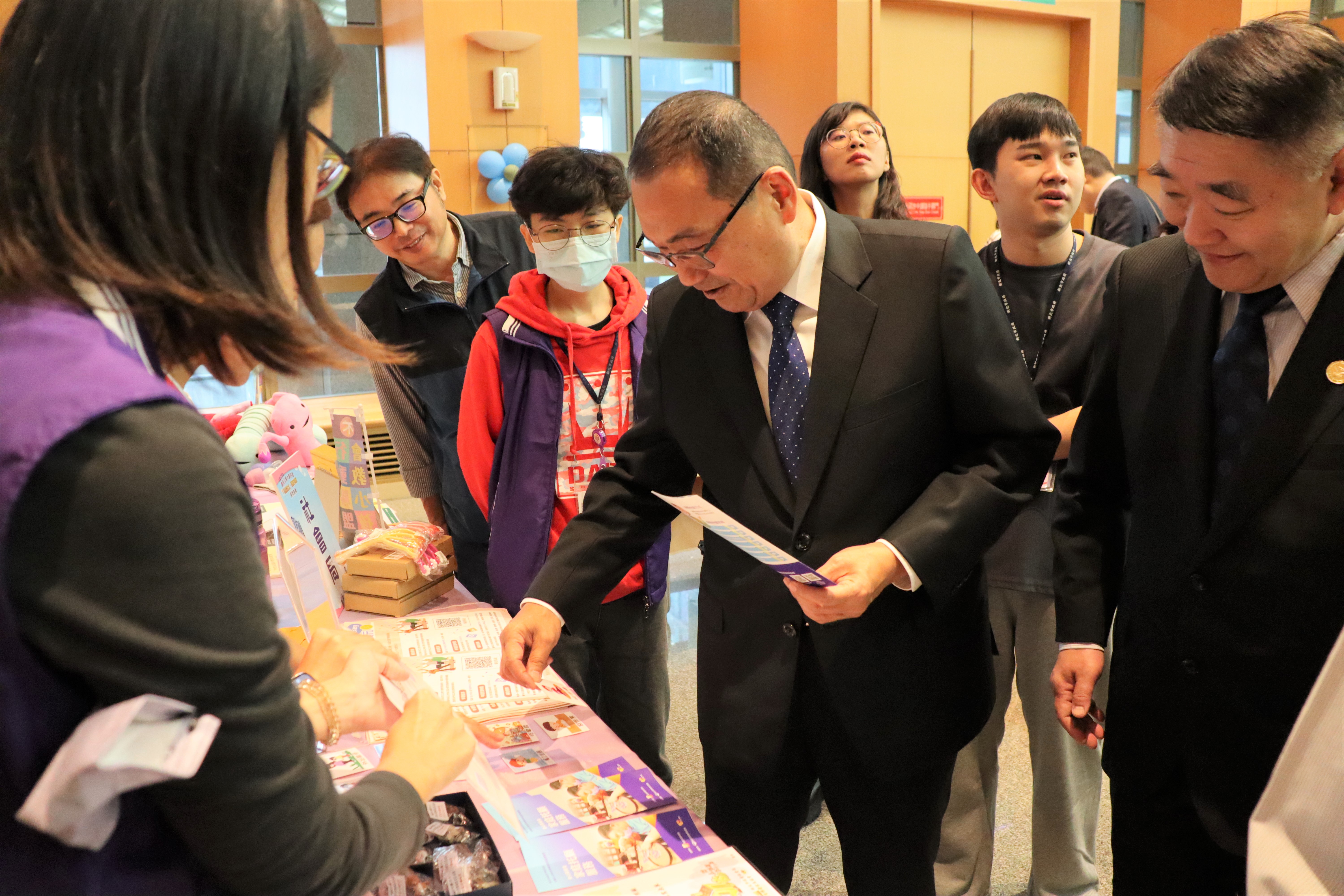 新北市長侯友宜主持113年度優良公寓大廈評選頒獎典禮後，工務局長馮兆麟（右）陪同市長參觀現場公寓大廈種子教師設置的銀鬆俱樂部先修班攤位，並感謝種子教師協助市府推動公寓大廈事務。