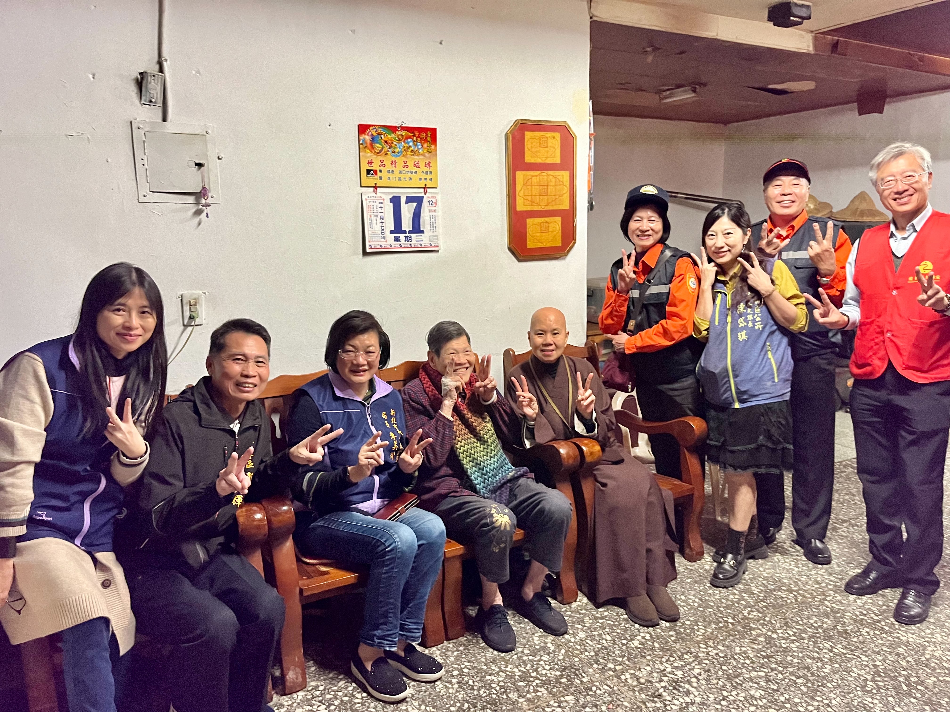 黃奶奶(中)人緣好，里長、街坊鄰居和社區巡守隊都喜歡找她聊天，眾人比著黃奶奶最喜歡的「YA」手勢合影