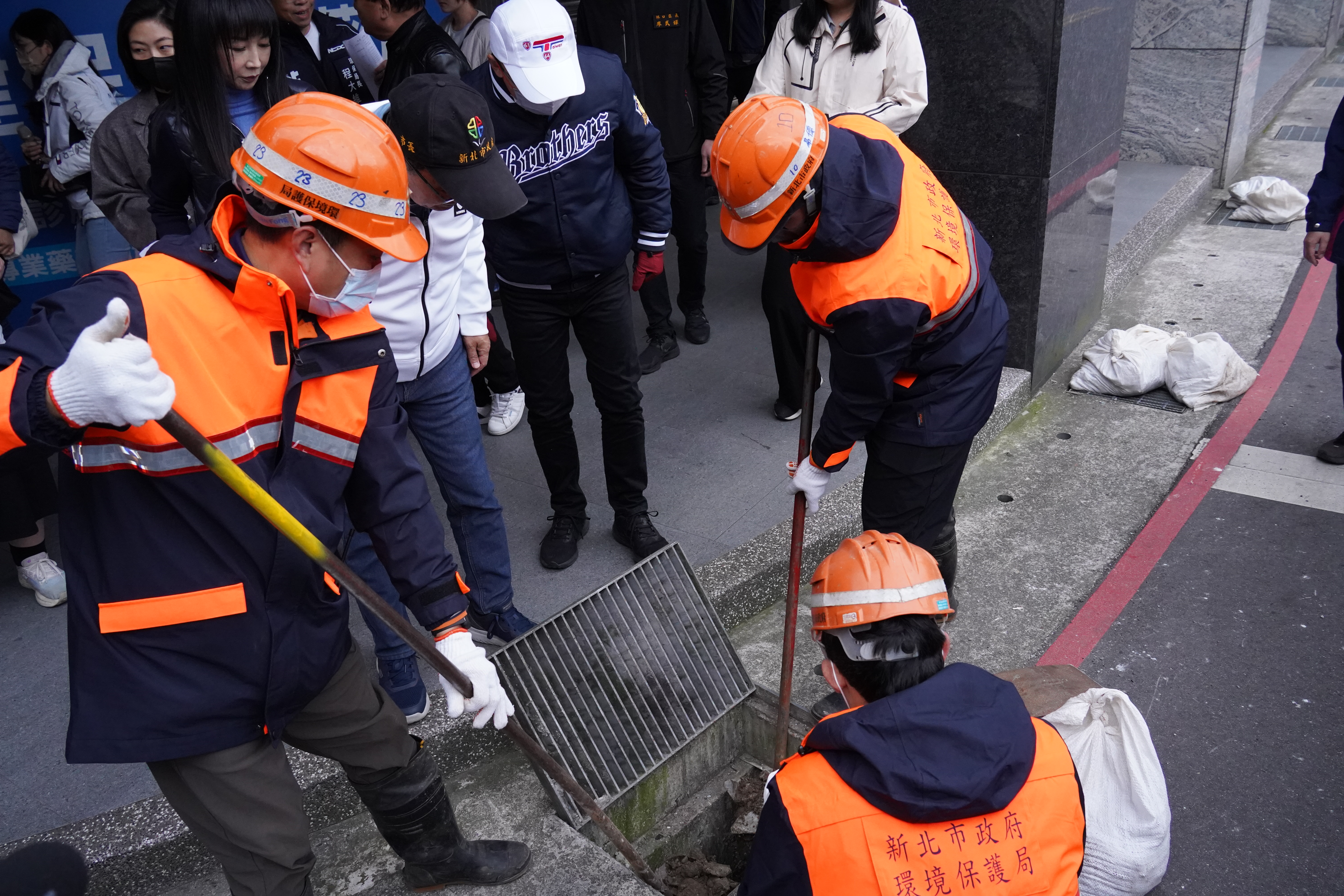清潔隊員手持清溝溝勺人力挖除落葉等雜物，以確保側溝保持通暢，避免雜物堆置影響排水功能