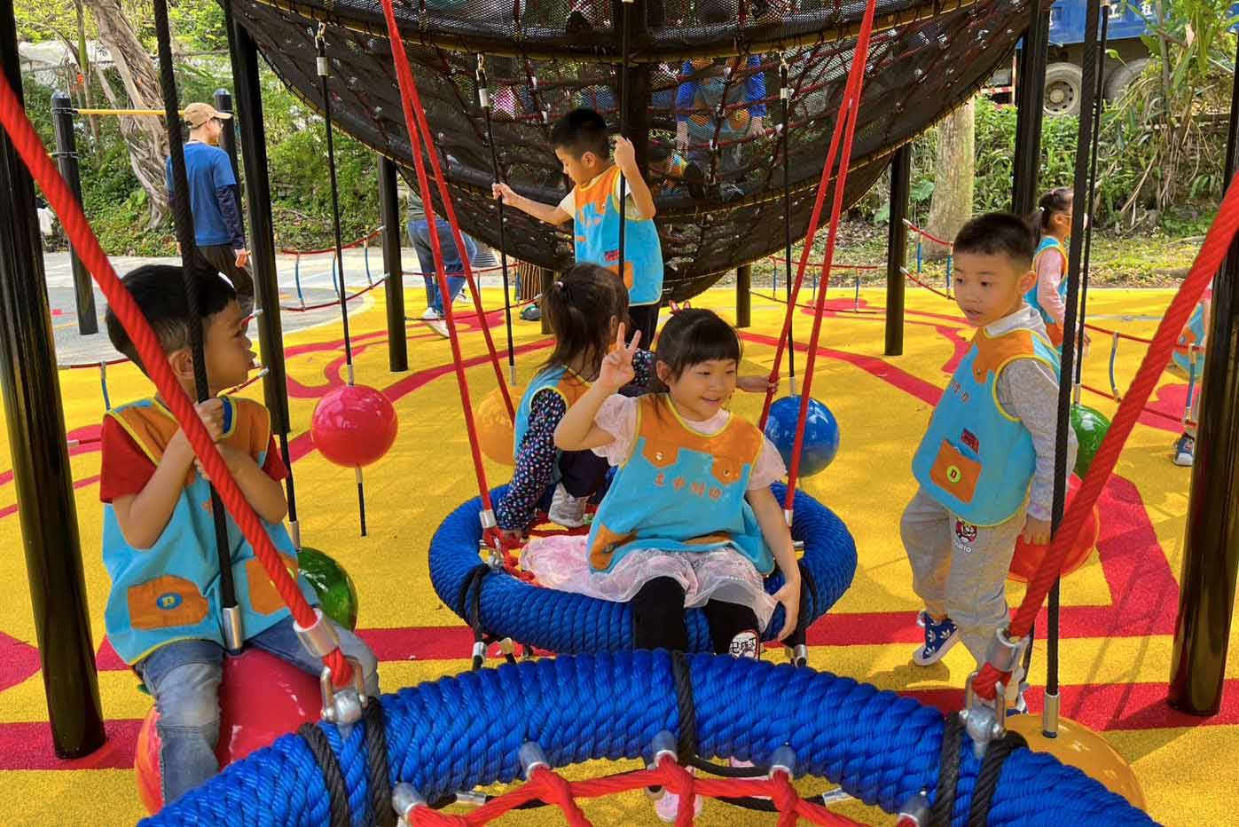 幼兒園孩童在鍬形蟲攀爬架下鞦韆，提升小朋友平衡能力