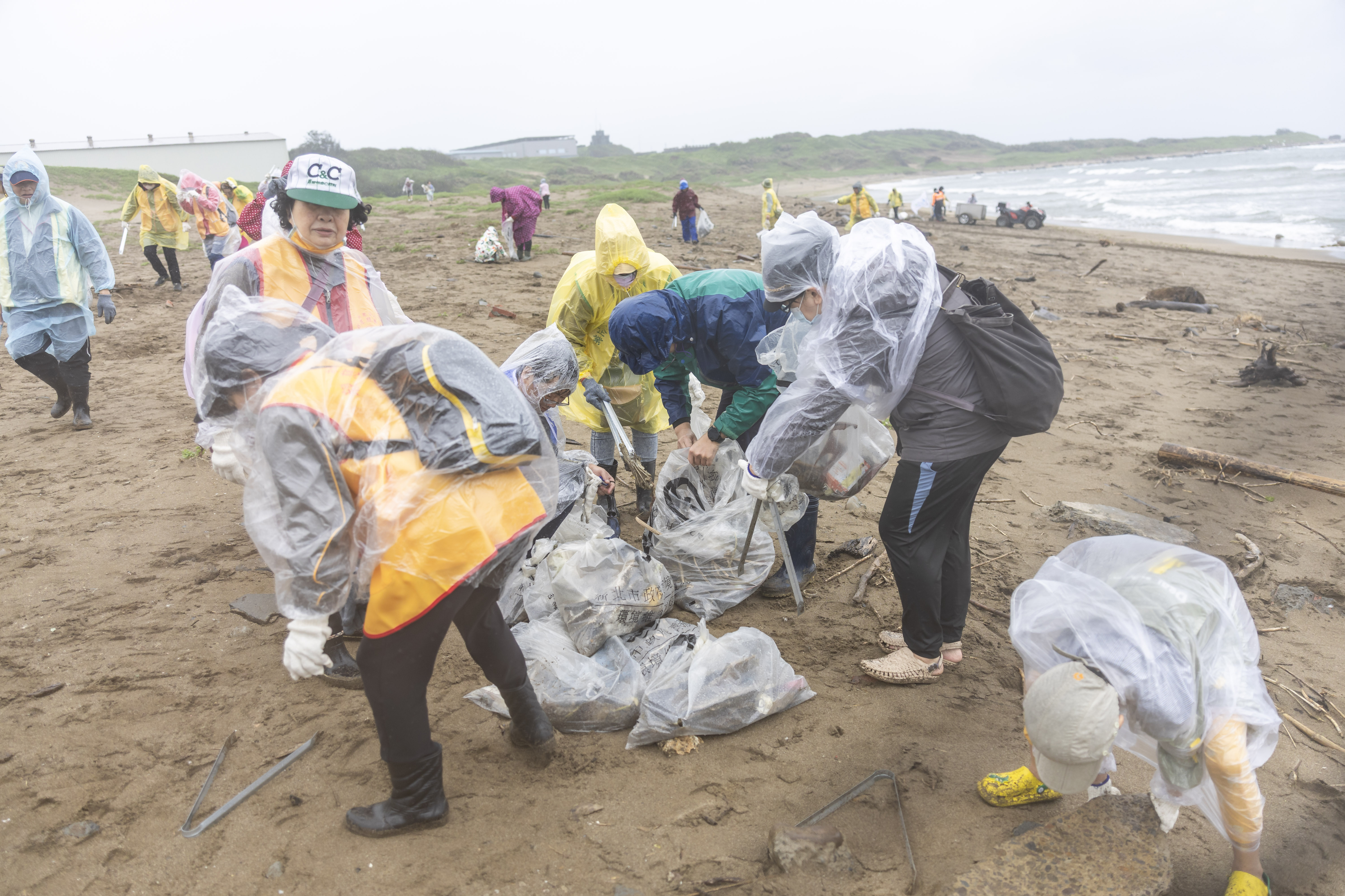 本次淨灘現場颳風下雨，依舊無法澆熄大家守護地球的熱情，穿著雨衣穿梭在沙灘上清理大大小小的海廢垃圾