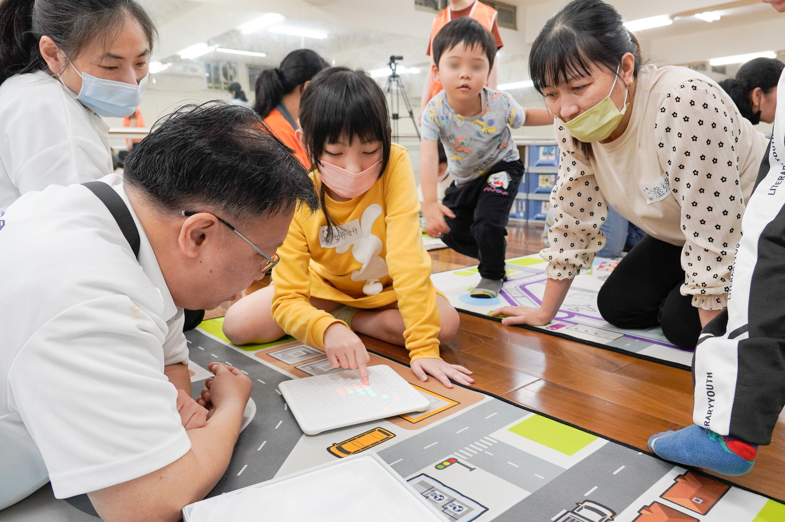 社團法人中華民國遊戲協會理事長林君英(左1)向孩子示範玩具的玩法 家長在一旁學習
