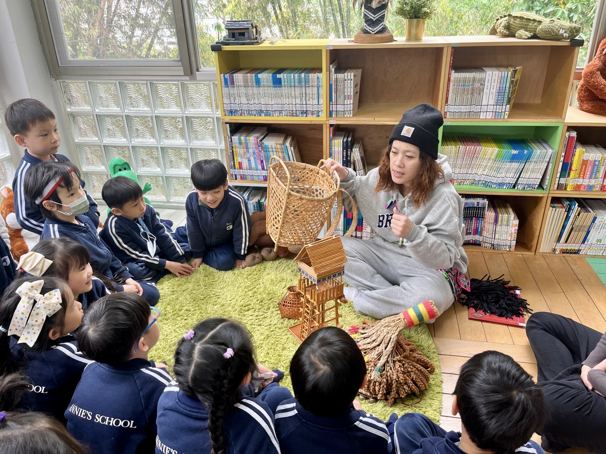 ▲說故事老師與小朋友分享原住民族傳統的背簍、小米等。(圖/新北市政府原民局提供)