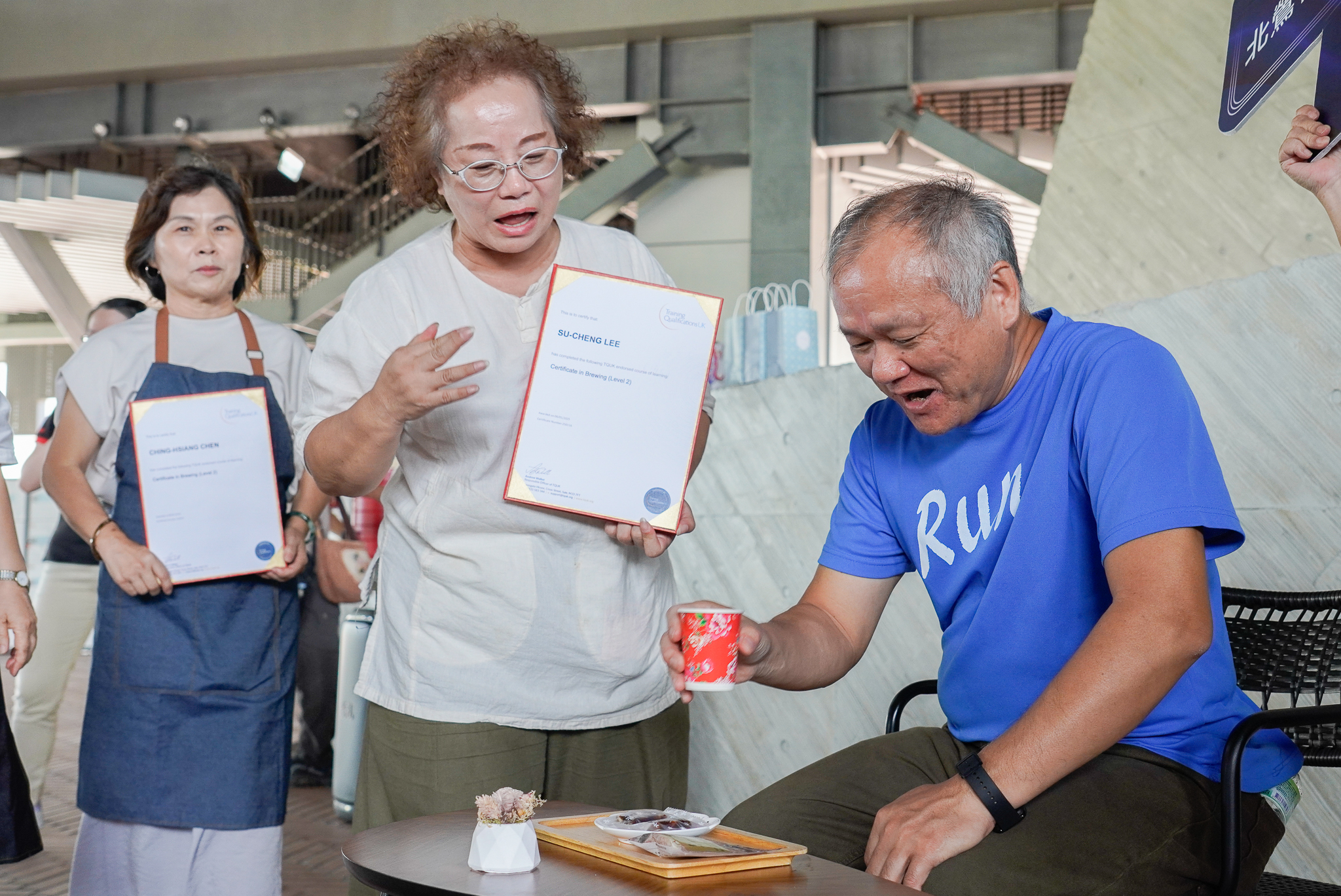 挑戰成功的民眾享用美味咖啡及茶點，北鶯社區發展協會理事長李素貞(中)介紹這咖啡是由社區培訓的國際認證手沖咖啡師所沖泡。