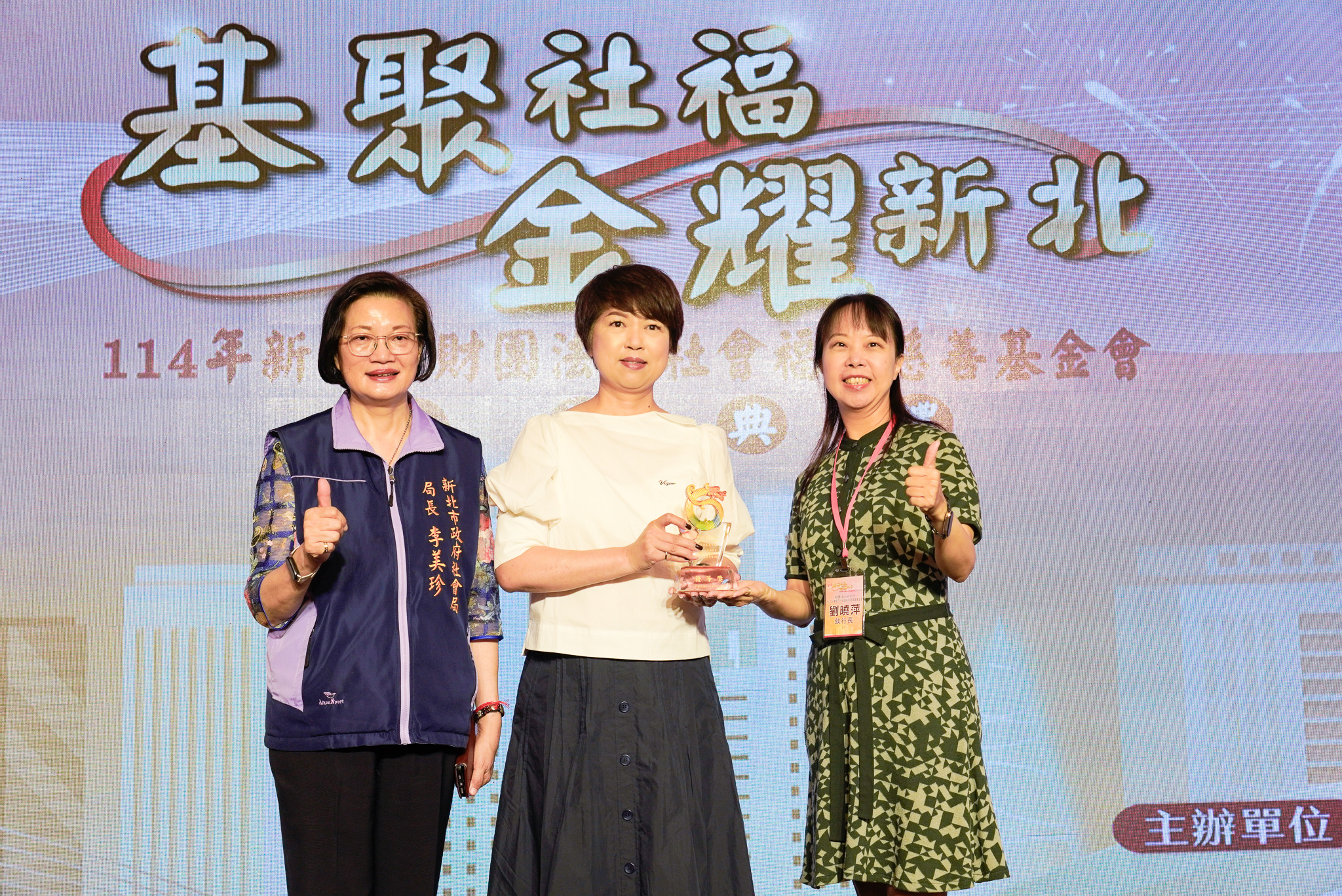 新北市副秘書長龔雅雯（中）代表侯友宜市長頒獎表揚鈊象電子社會福利慈善事業基金會執行長劉曉萍（右）