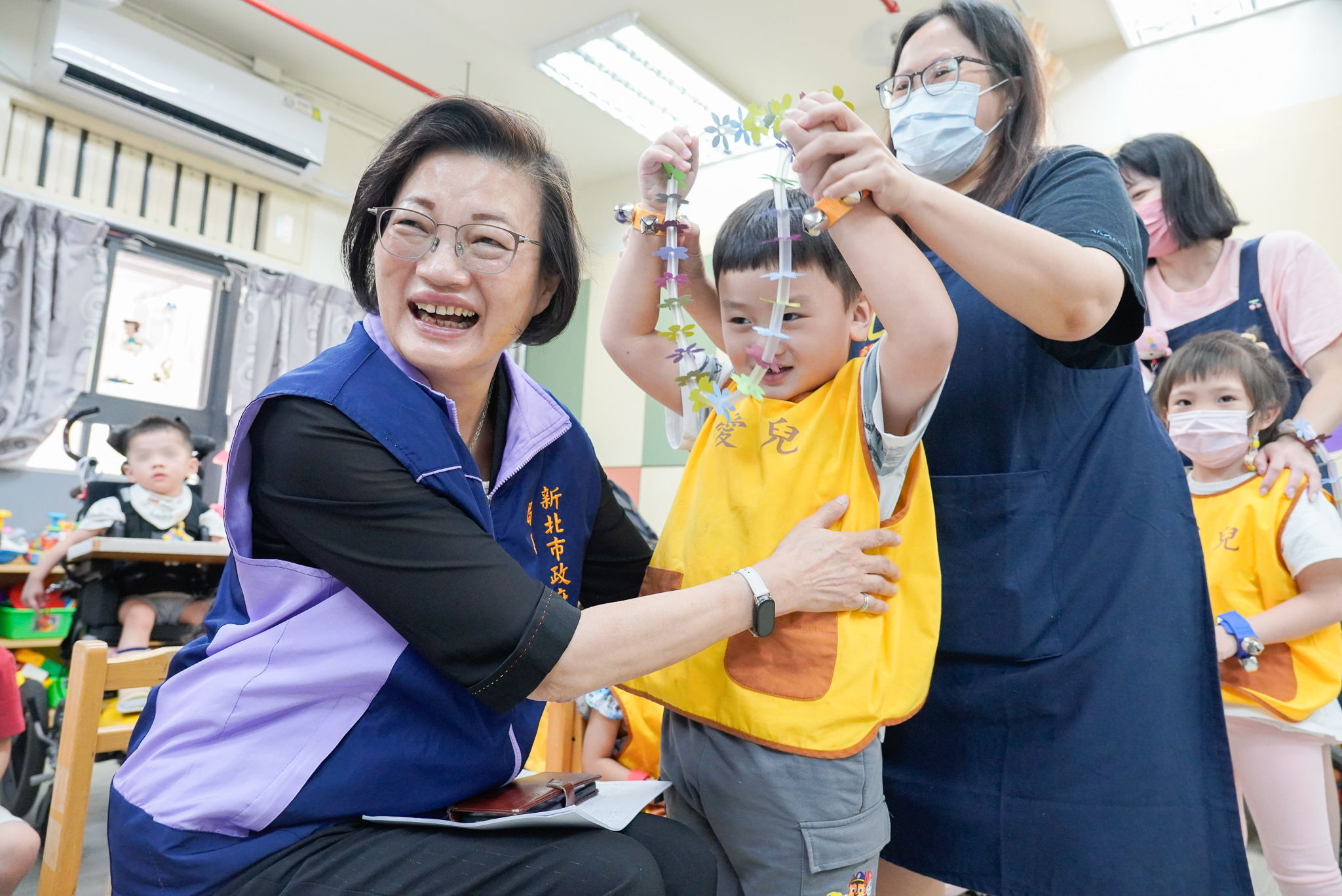  愛兒兒發中心的威威要代表中心獻上自製的小花環給李美珍局長，卻直往自己脖子套，惹得眾人笑彎了腰。
