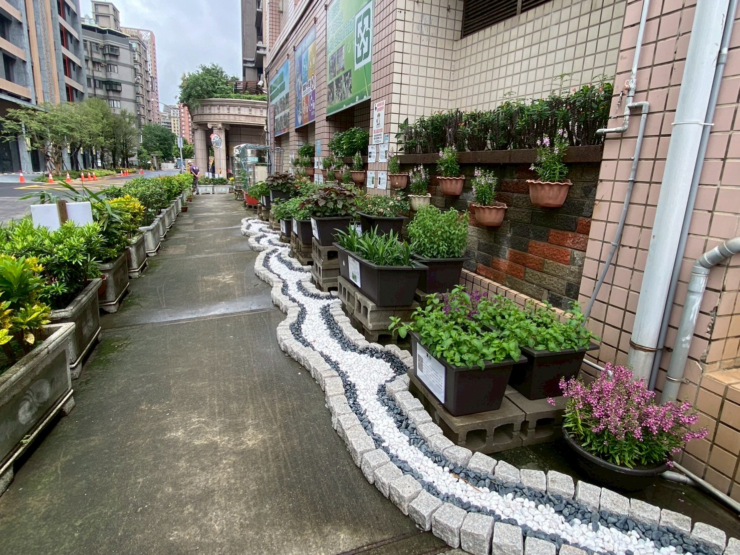 林口區仁愛里可食地景以雙色卵石營造出河道意象，輝映著五彩繽紛的可食性植栽，彷彿依著水道生生不息永續生長