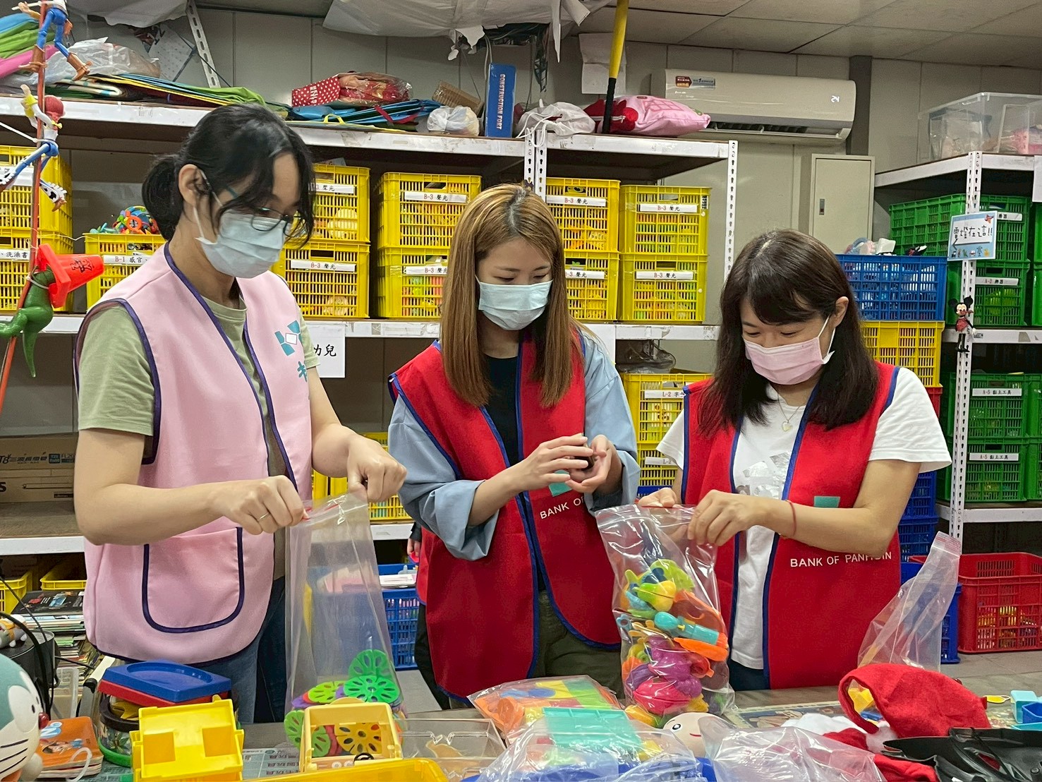 板信商業銀行業務部企劃科長黃依翎(左1)與員工合作整理二手玩具