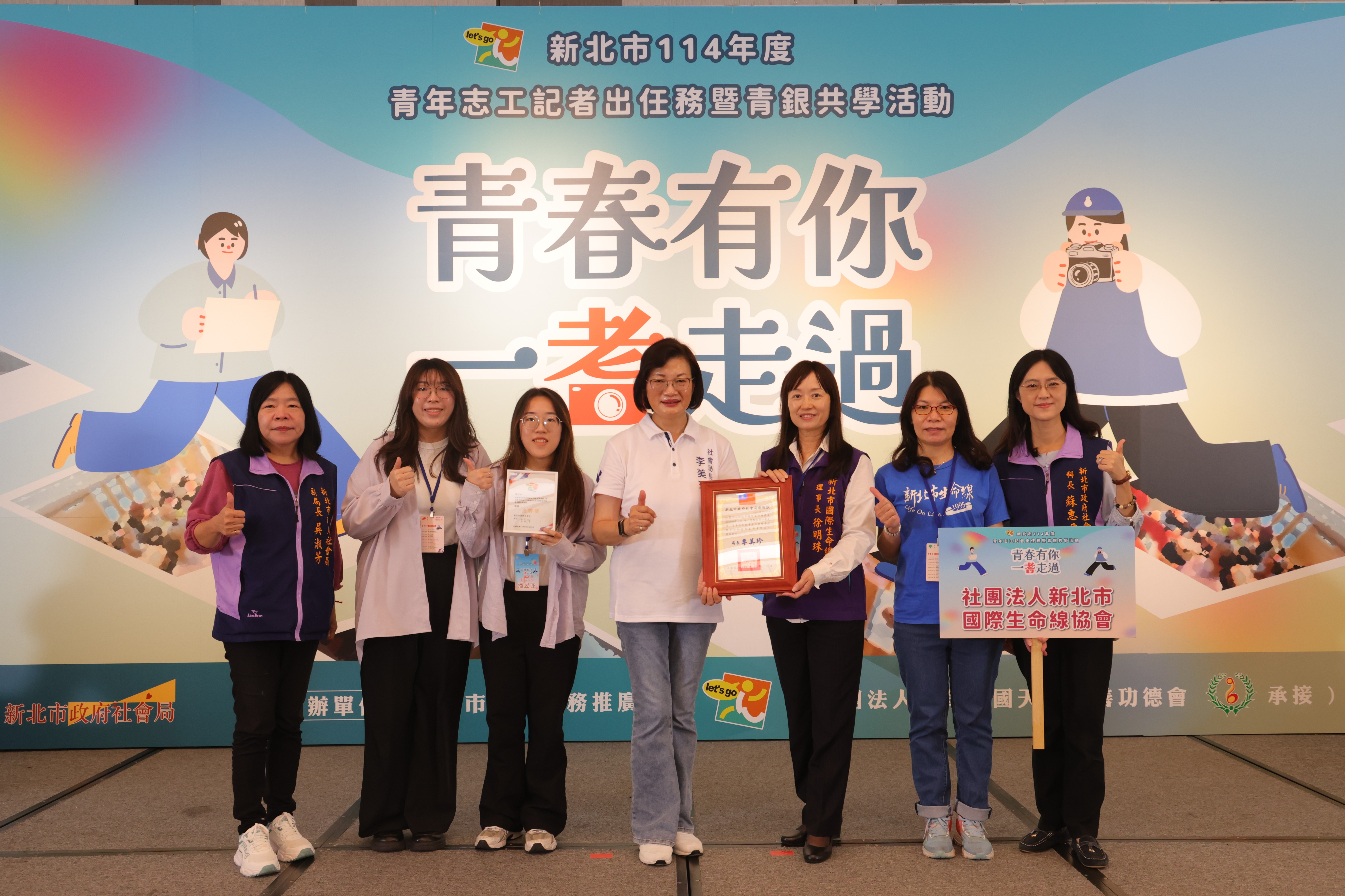 社會局長李美珍(中)頒獎鼓勵青年志工，圖為榮獲「金牌獎」青年志工記者潘昱亦(左3)及潘昱伃(左2)合影