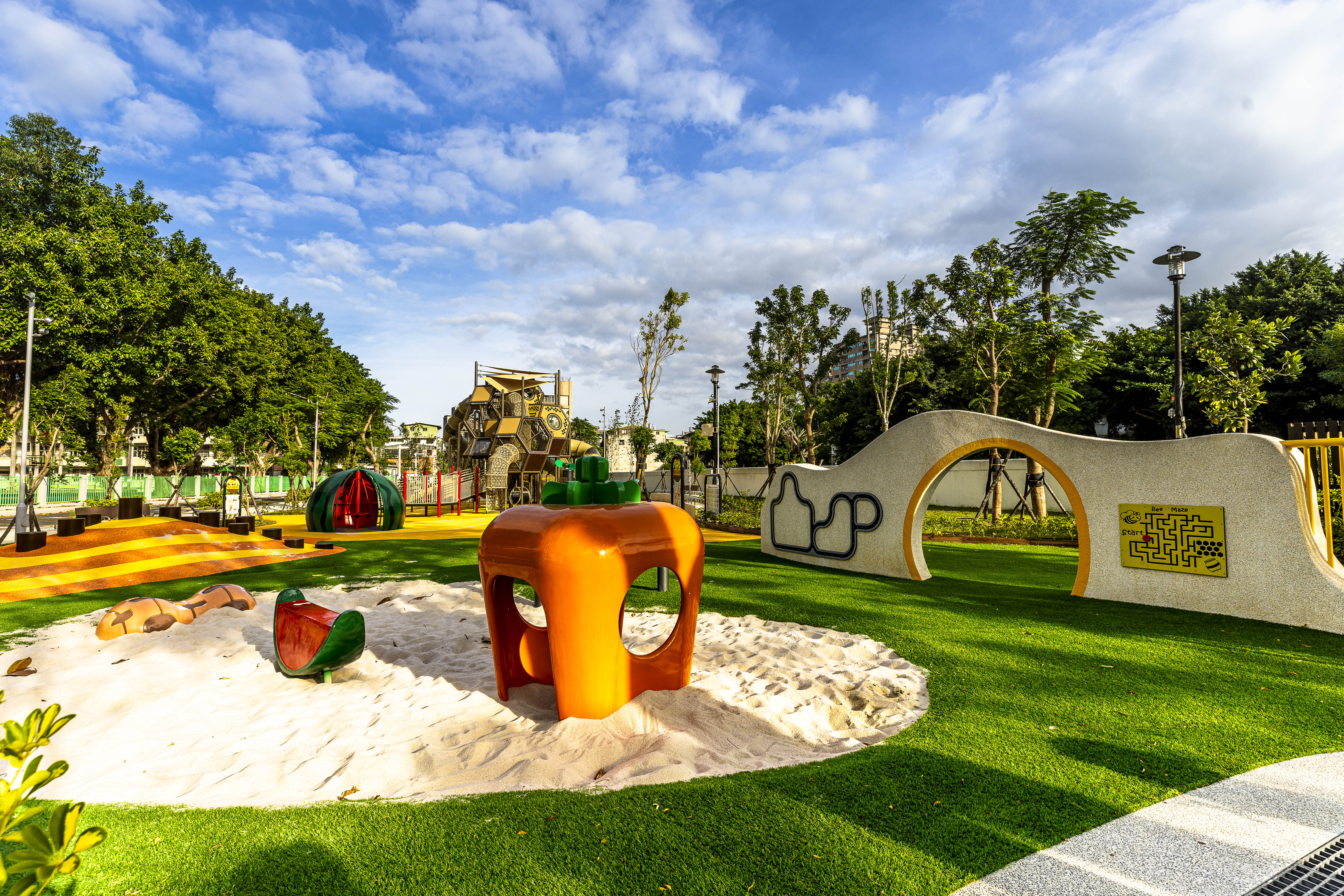 新莊區快樂公園設置共樂地景沙坑區、蜂巢主題遊戲區、健康樂活區等五大區，提供長者孩童、行動不便者都能安心往來。