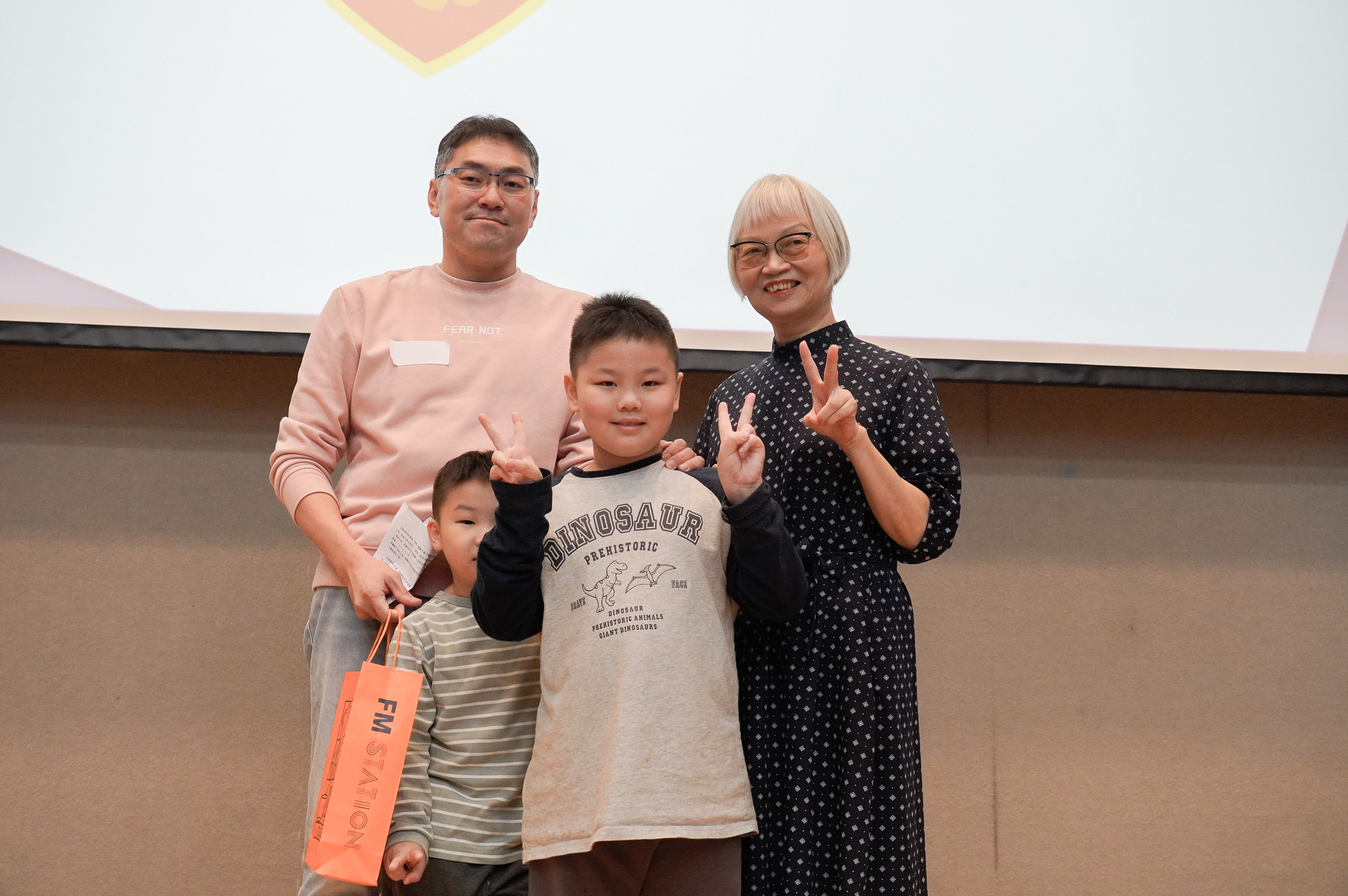阿勝獲得「家長有夠讚」獎，他說曾缺席孩子人生89天，收到孩子用注音寫「爸爸我好想你」的信，不自覺地落淚。他現在在教會擔任特別班老師。右為聞哲全人教育基金會董事長連素株