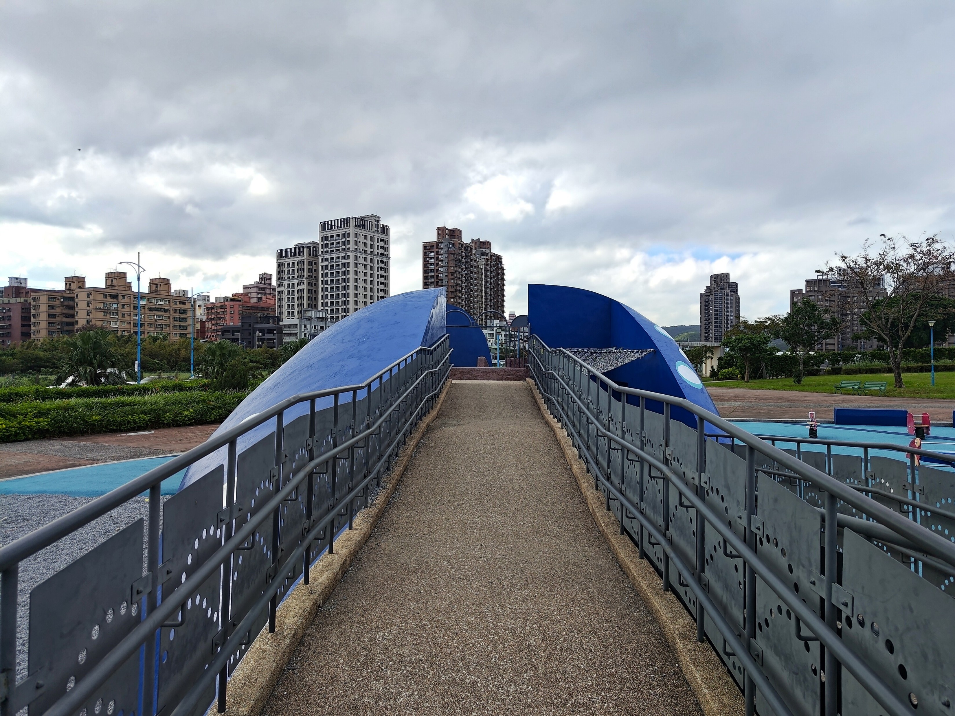 八里區商港公園鯨魚造型溜滑梯，左右兩側分別以攀爬梯及無障礙坡道提供不同遊戲路徑