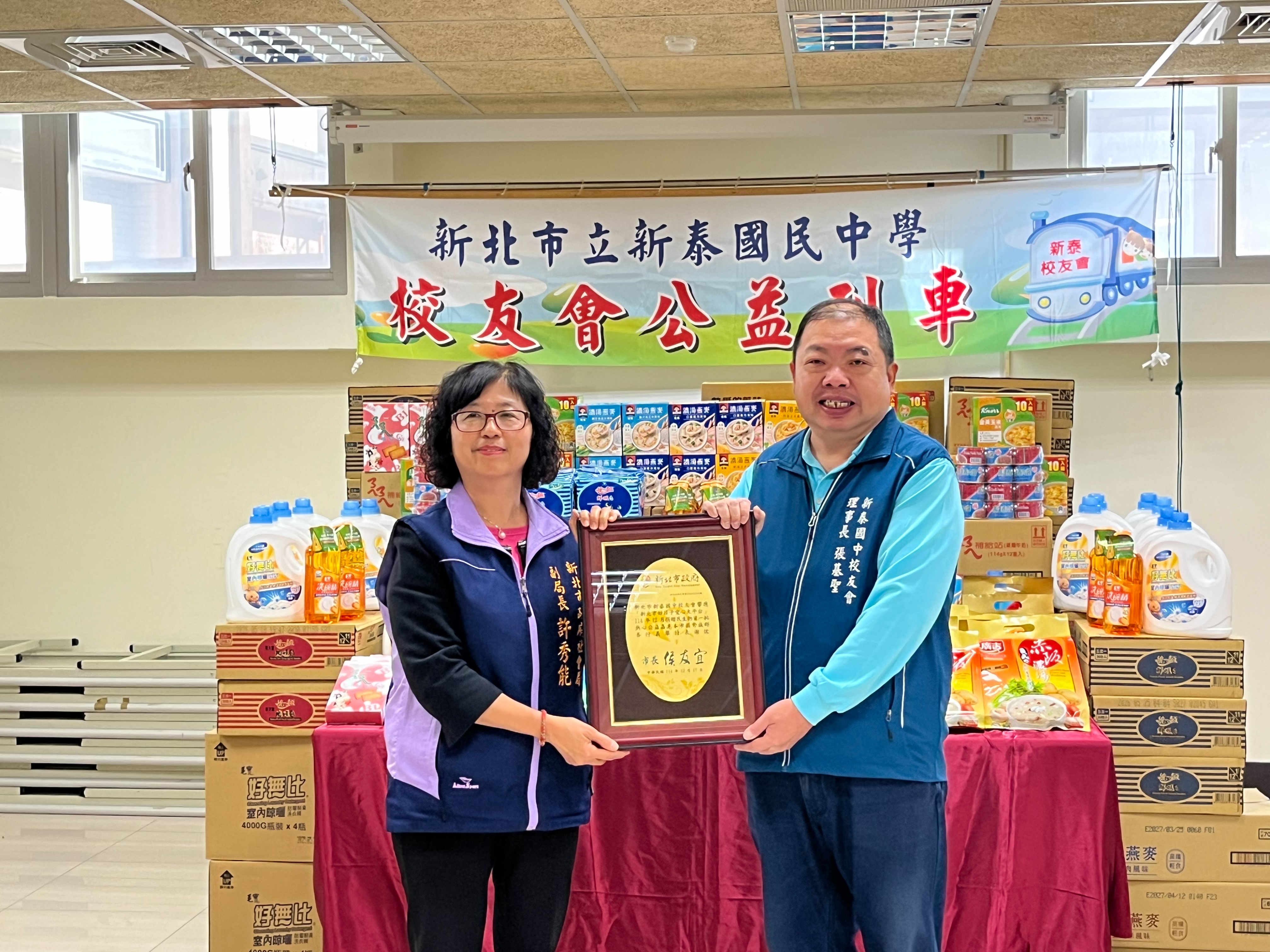 新北市新泰國中校友會張基聖理事長(右)代表捐贈民生物資，社會局副局長許秀能(左)出席受贈並致贈感謝牌