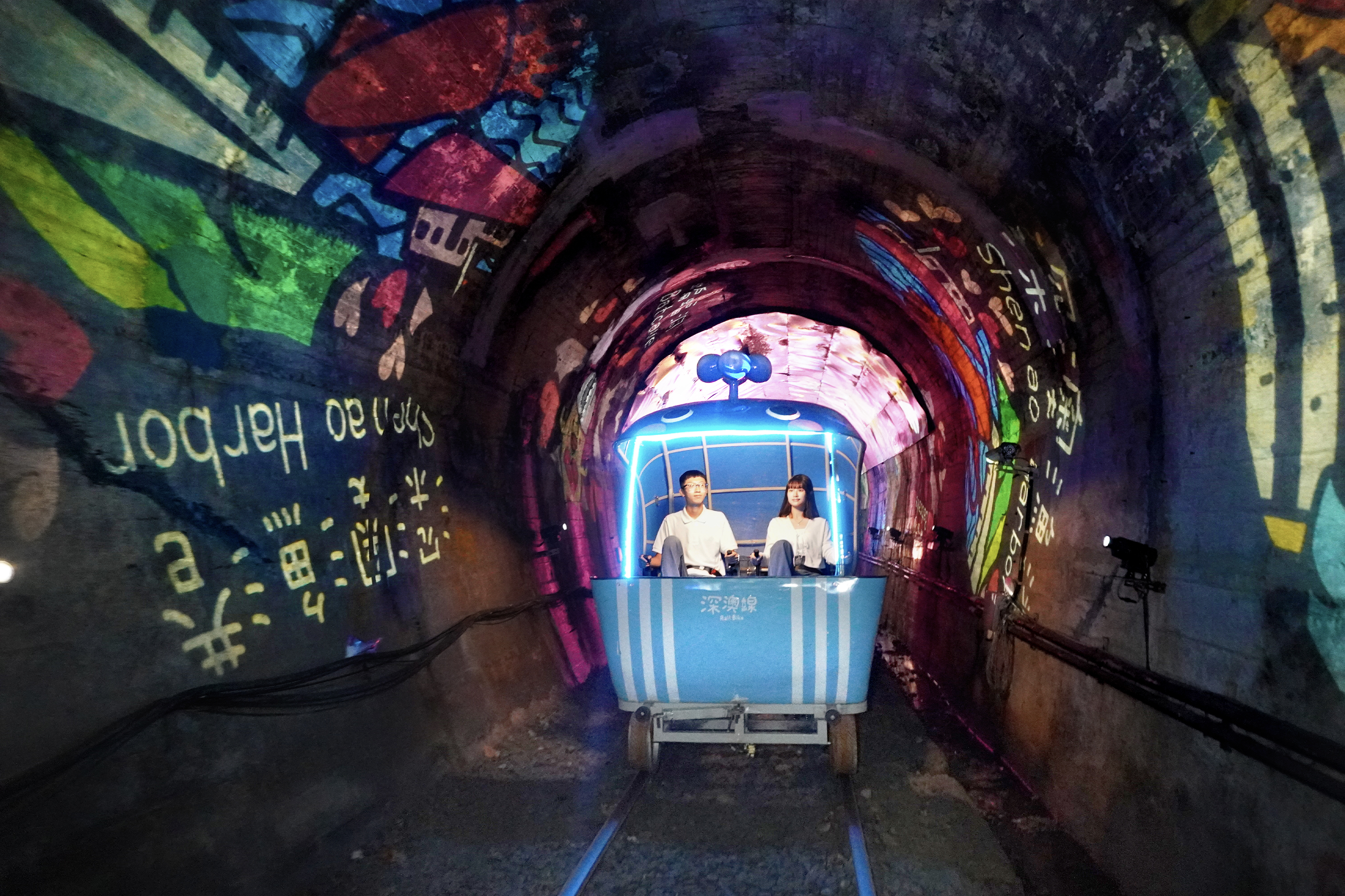 騎進深澳鐵道自行車光隧道，投影燈映照周邊特色景點，彷彿在光影中展開一場深澳小旅行。