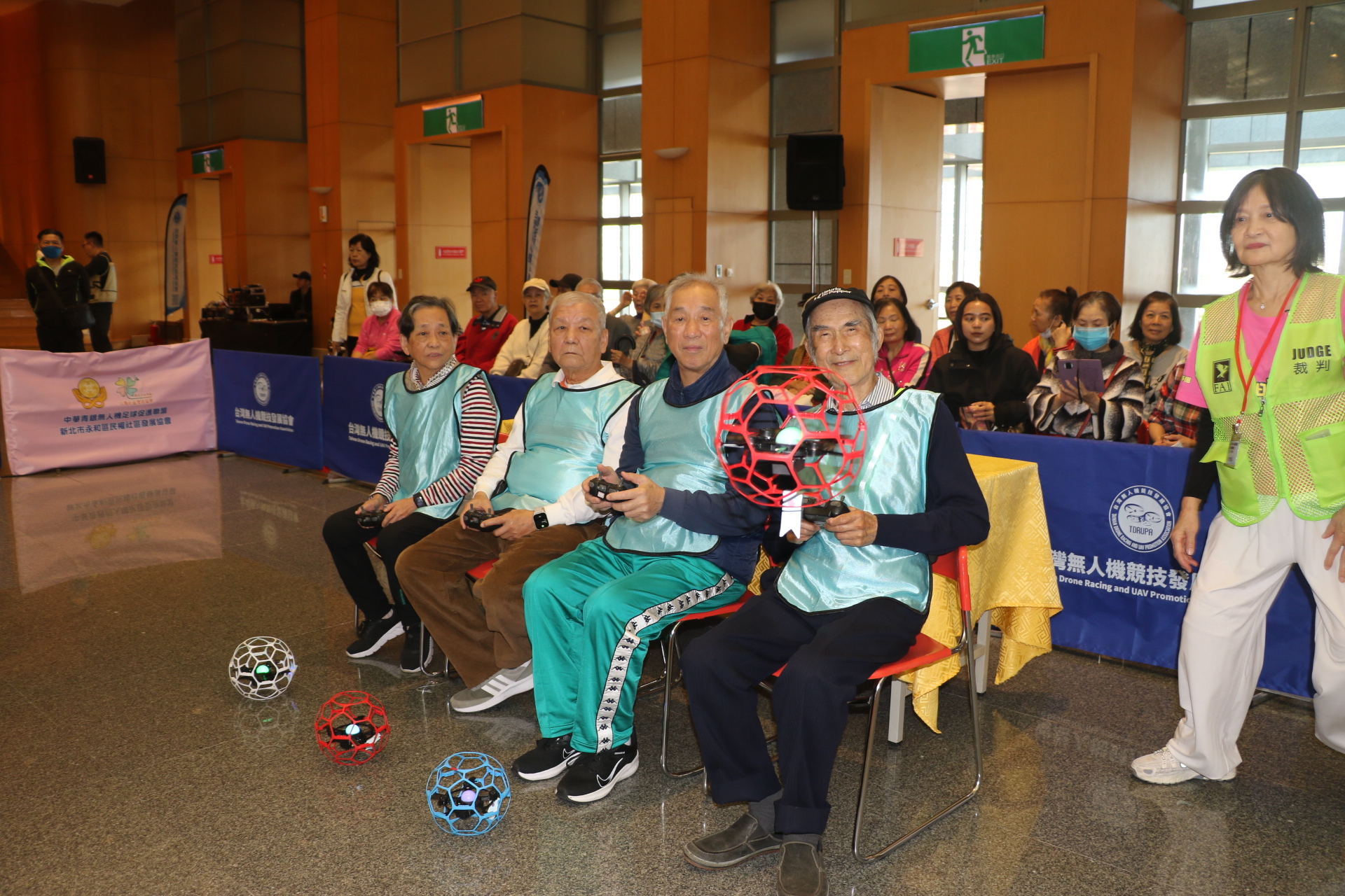  永和民權據點外號「多啦A夢」的韓大雄（坐者右1），操作無人機足球起飛瞬間