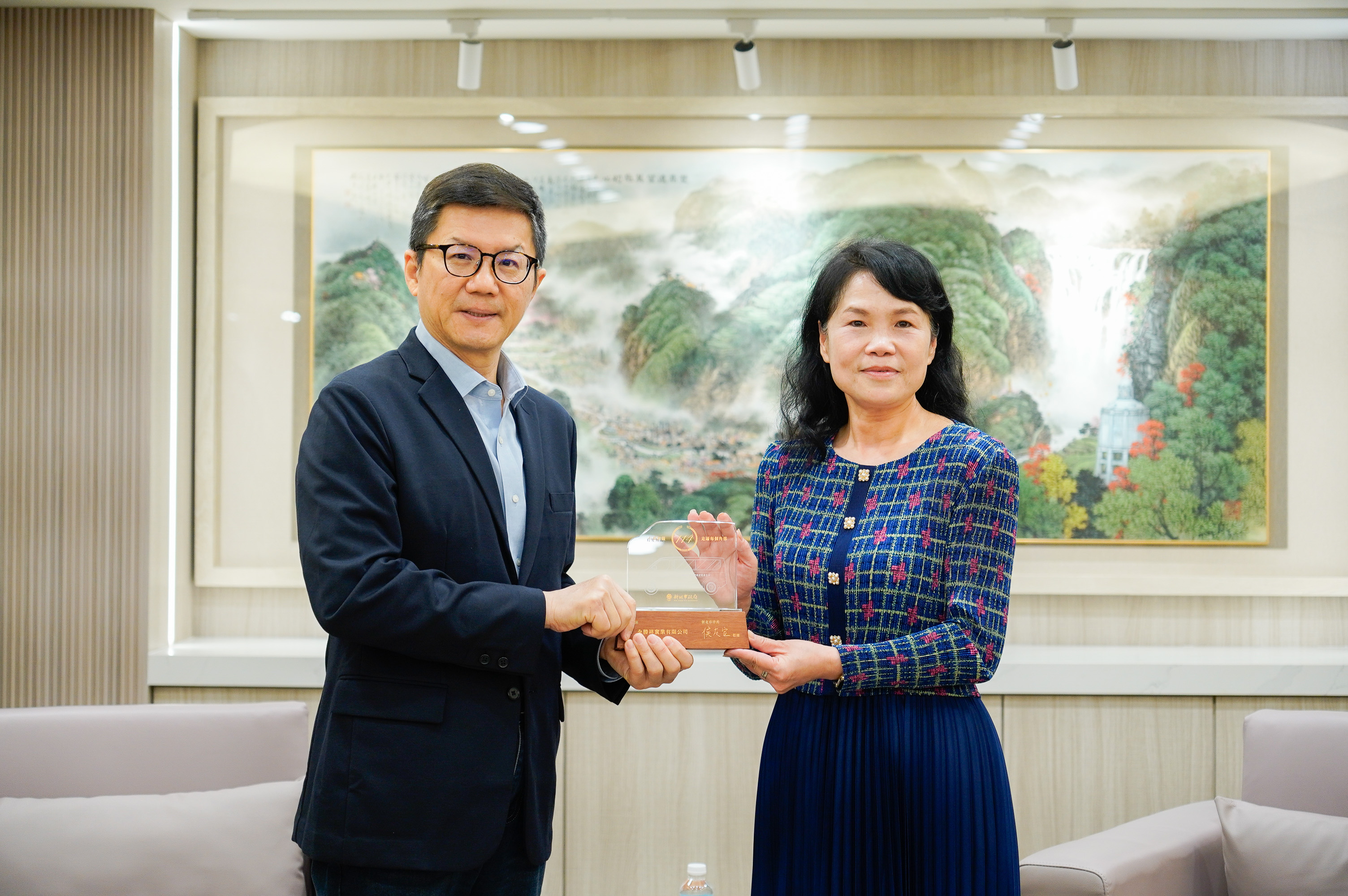 全勝祥實業有限公司執行長褚美雲(右)捐贈復康巴士，由新北市副秘書長張其強(左)代表受贈並回贈感謝獎牌及紀念座