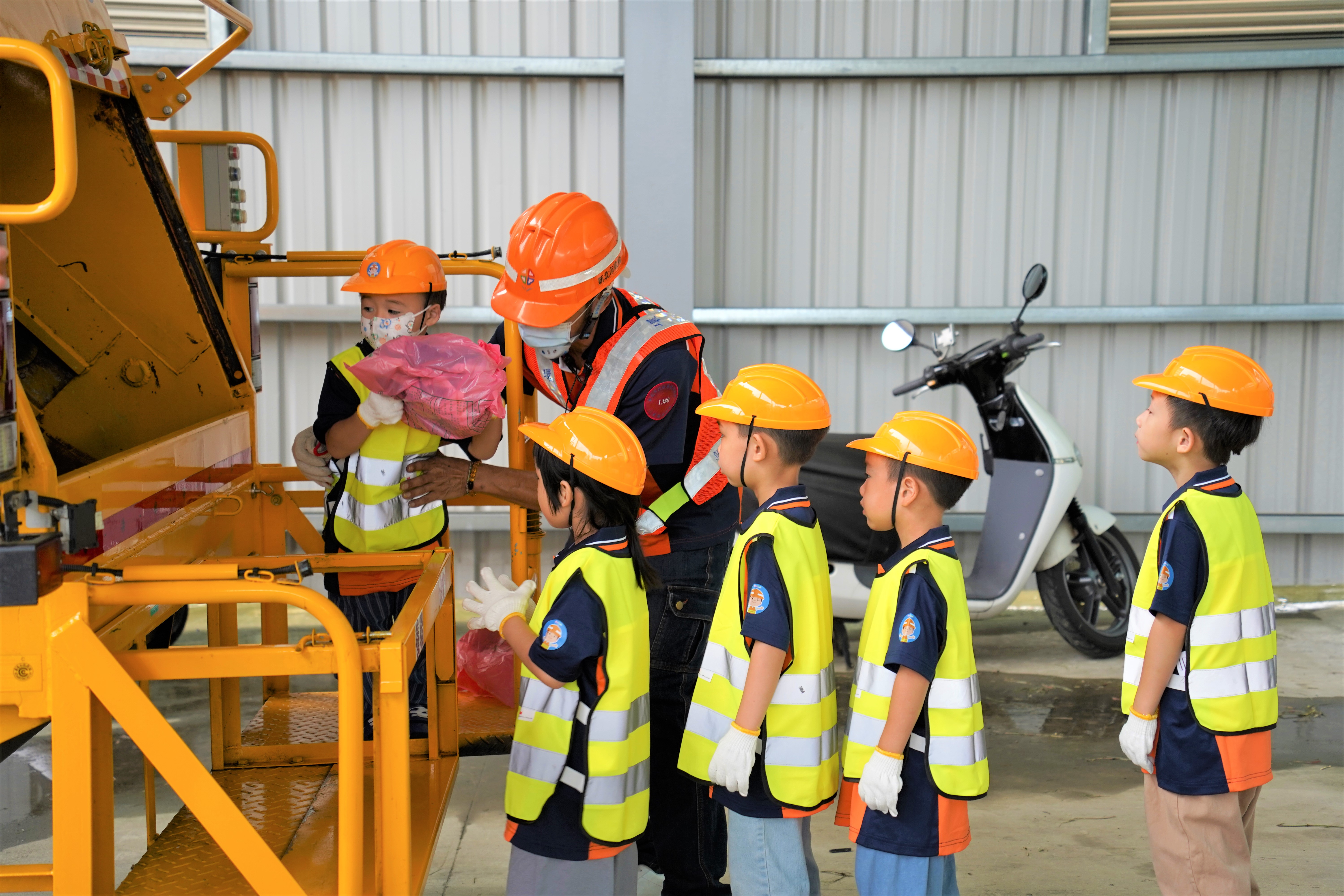 小小清潔隊員將垃圾丟入垃圾車，體驗垃圾清運的過程