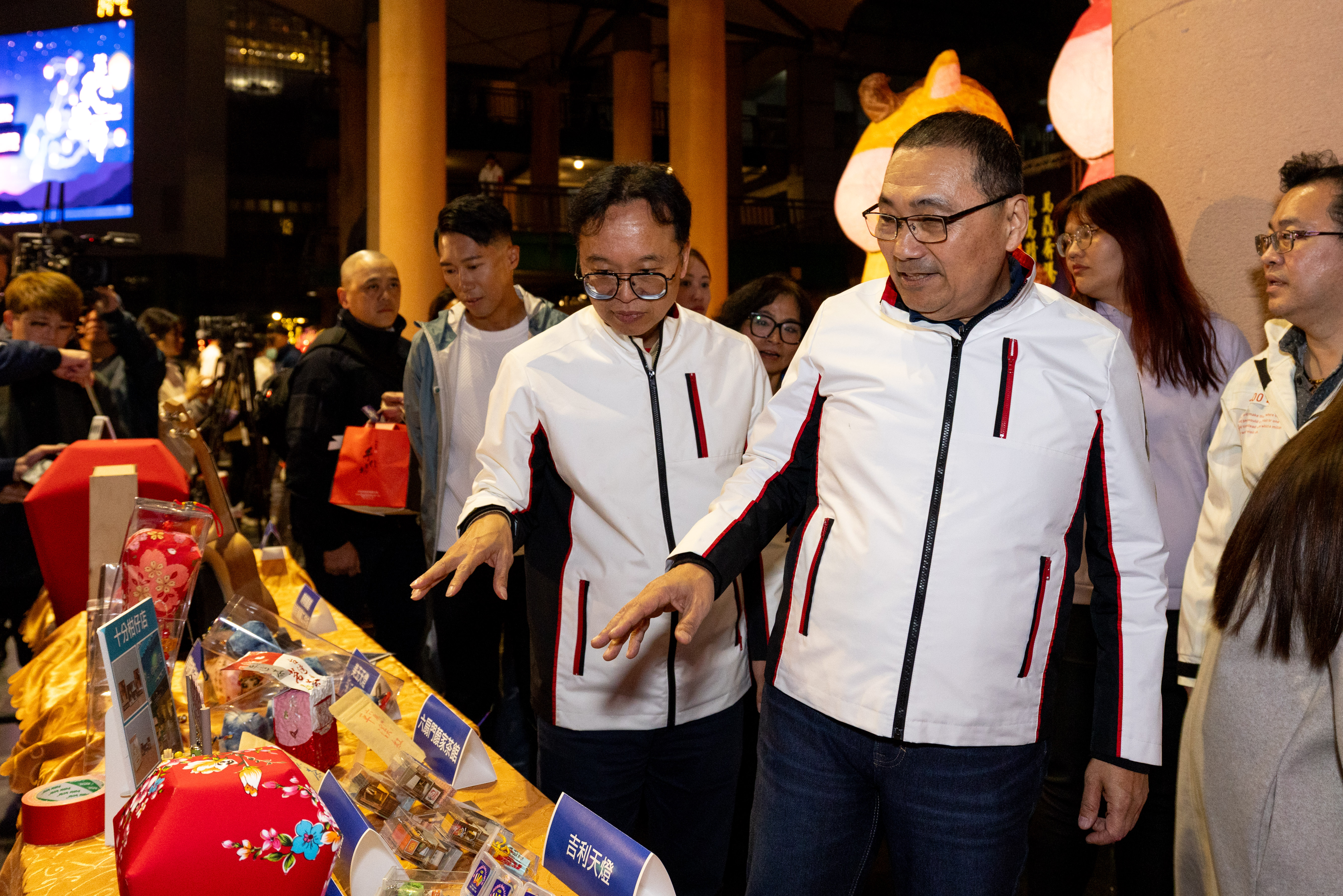  侯友宜市長、代言人陳彥博與觀旅局長於平溪商圈攤位上參觀在地特色文創商品。